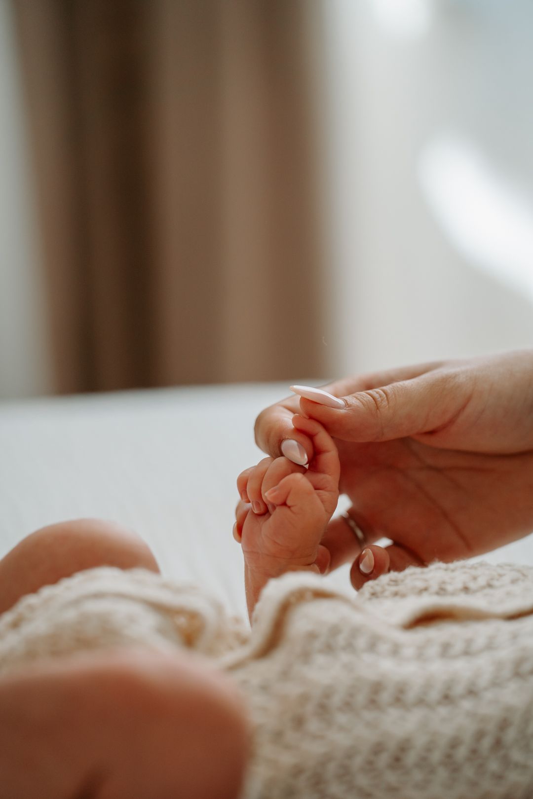 Close-up view of gentle hands holding a soft knitted blanket in warm natural lighting.