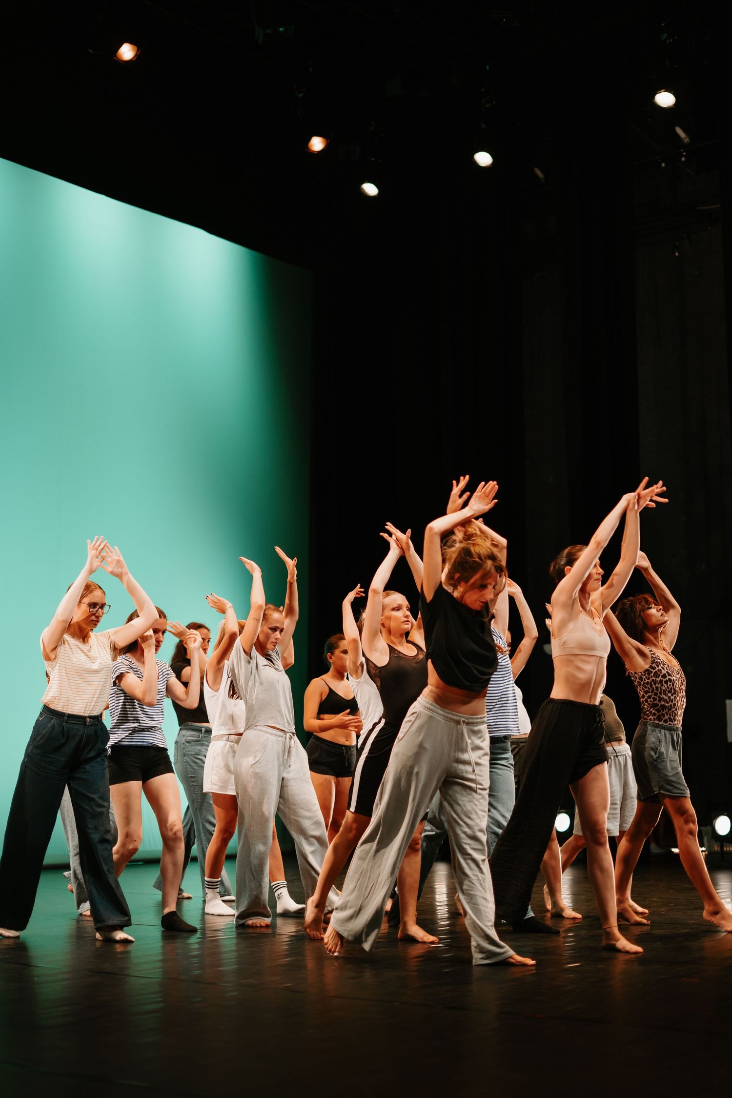 Modern dancers perform a synchronized movement sequence on stage with dramatic lighting and flowing choreography.