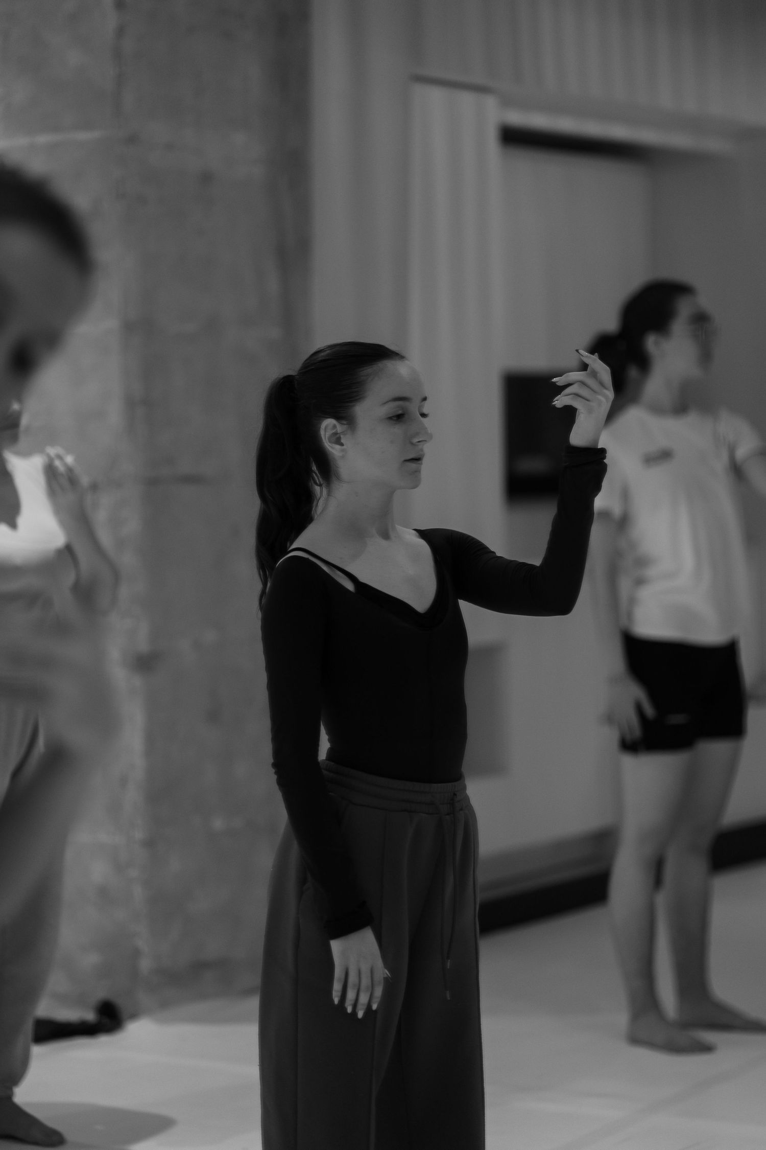 A sequence of black and white photos showing a dancer performing expressive movements in an indoor space.