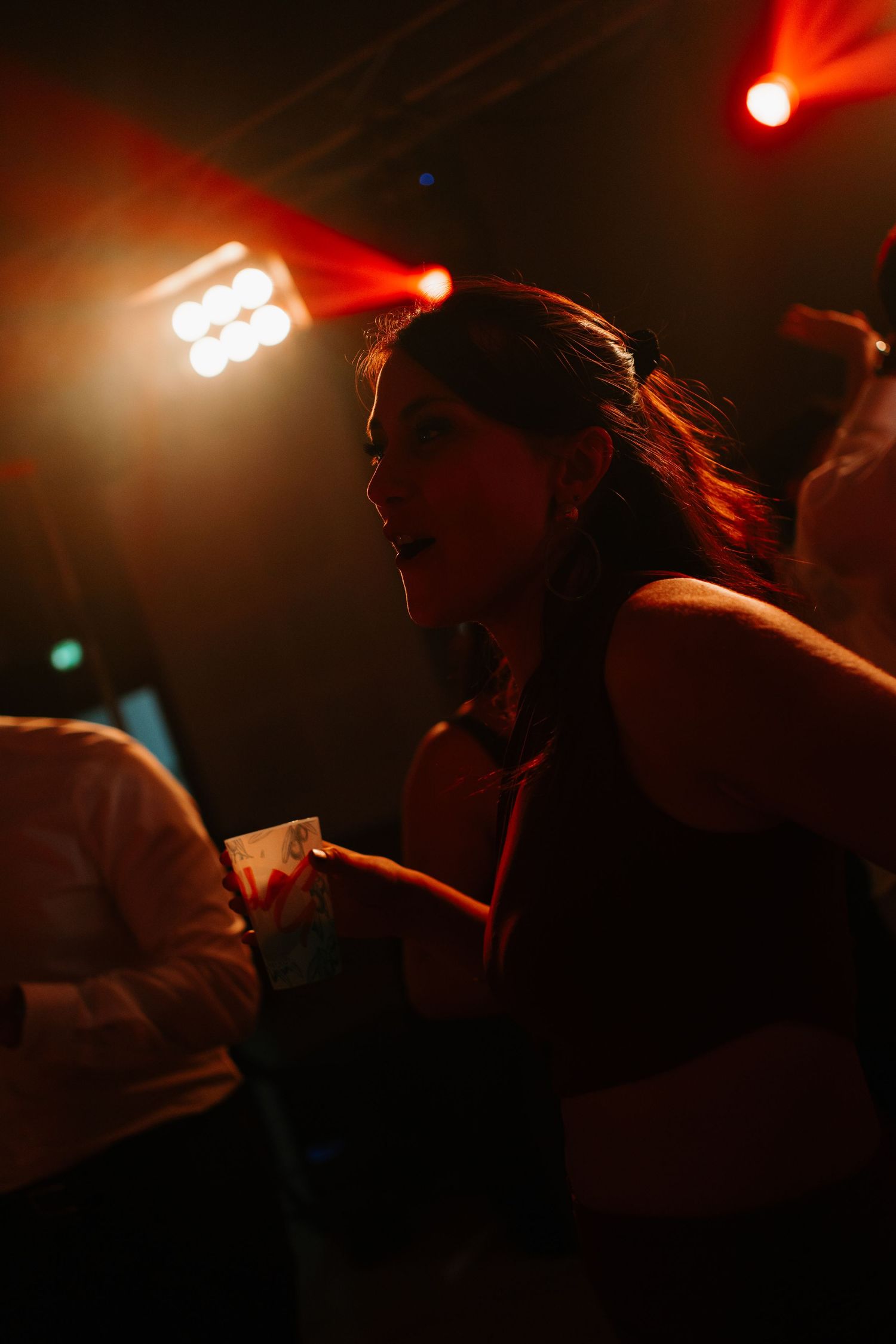 A silhouetted figure dances energetically under dramatic red stage lighting at a nightclub or concert venue.