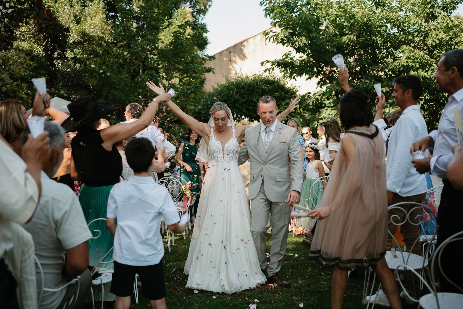 Wedding guests dance and celebrate together in an outdoor garden reception with a mix of formal and casual attire.