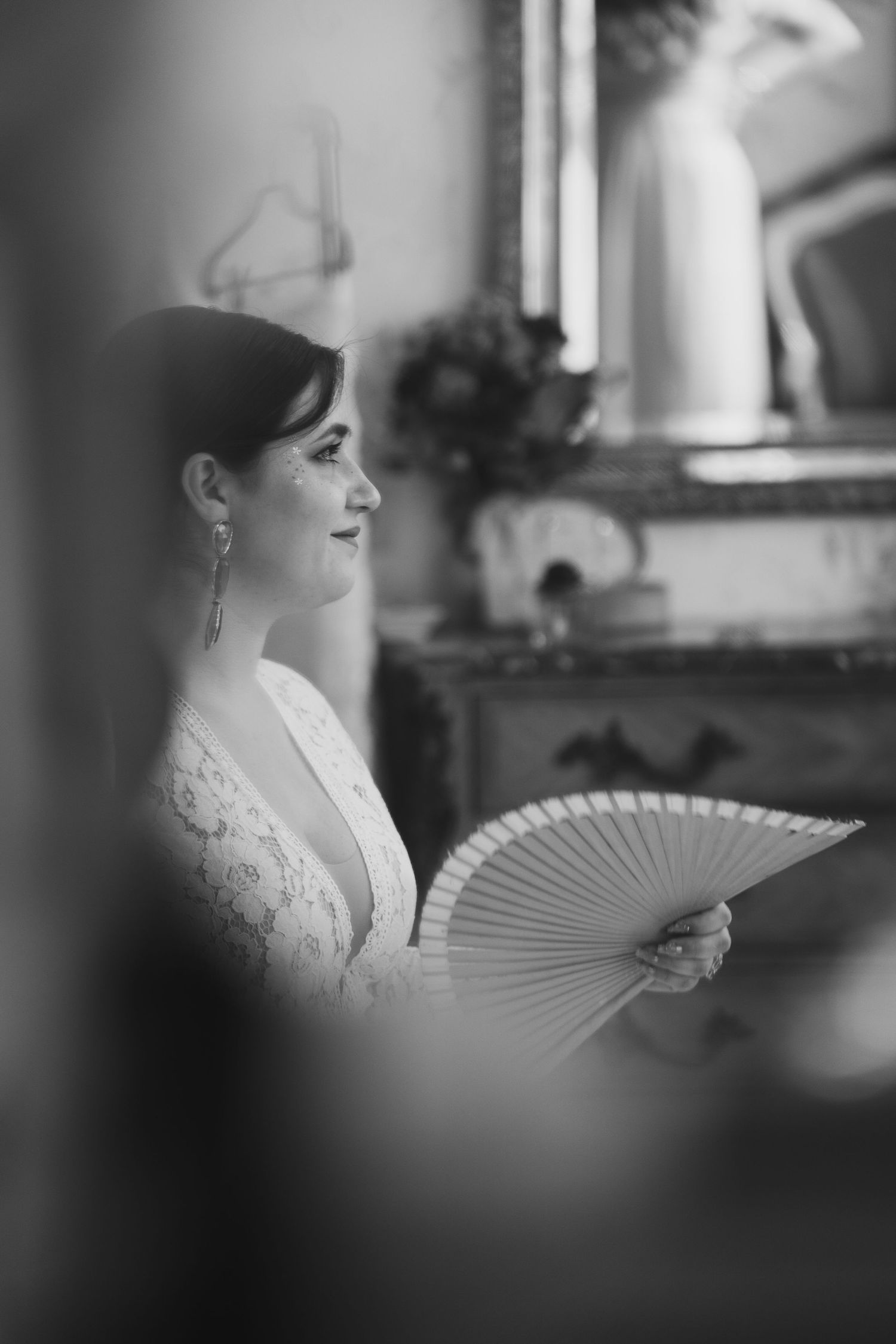 A black and white photo series showing a woman in vintage bridal attire holding a decorative hand fan.