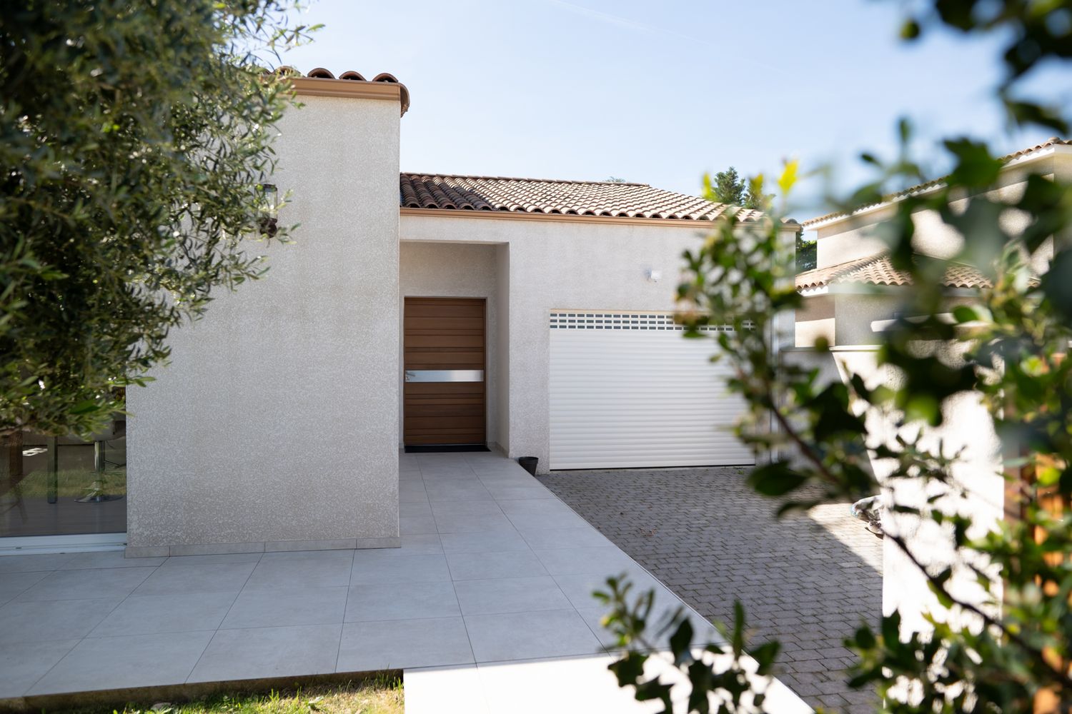 A series of white stucco buildings with terra cotta tile roofs and concrete pathways in a Mediterranean style setting.