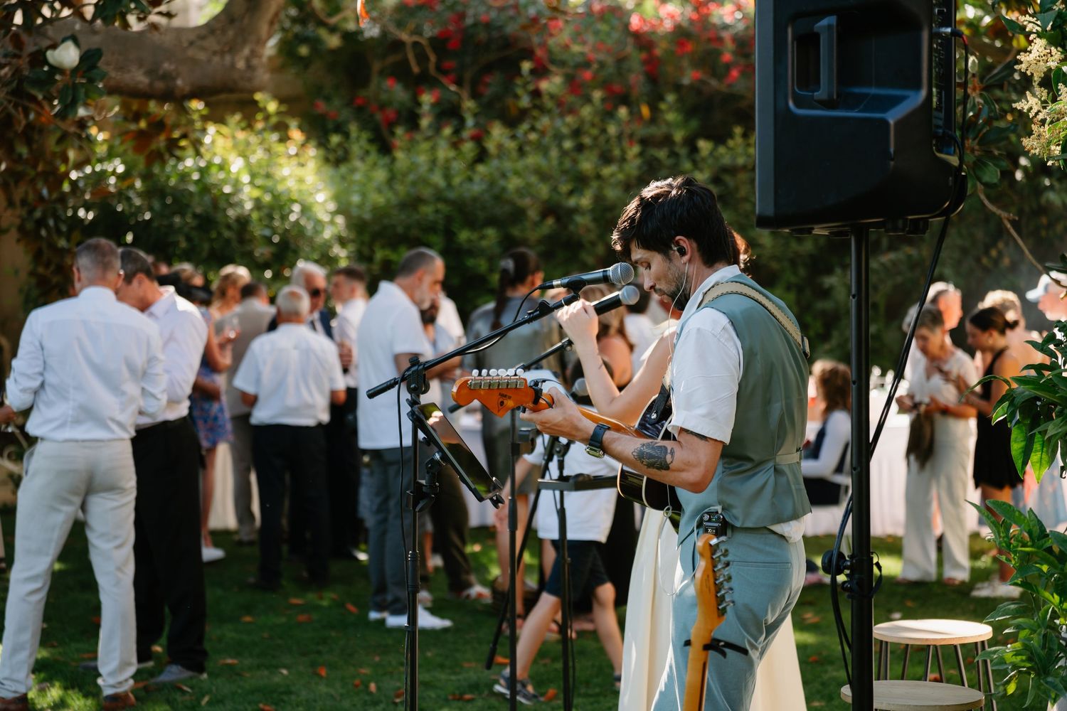 Wedding guests mingle and socialize in an outdoor garden setting during a summer celebration.