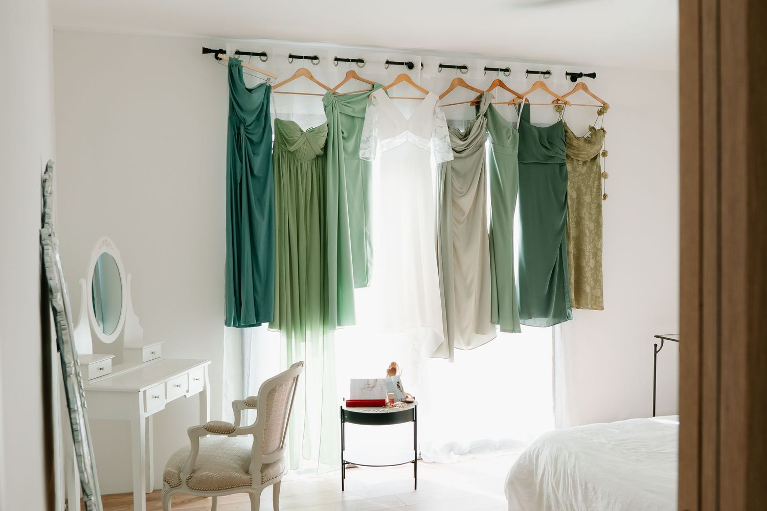 Vintage dressing room interior with green curtains, white walls, and elegant furniture arranged along mirrored walls.