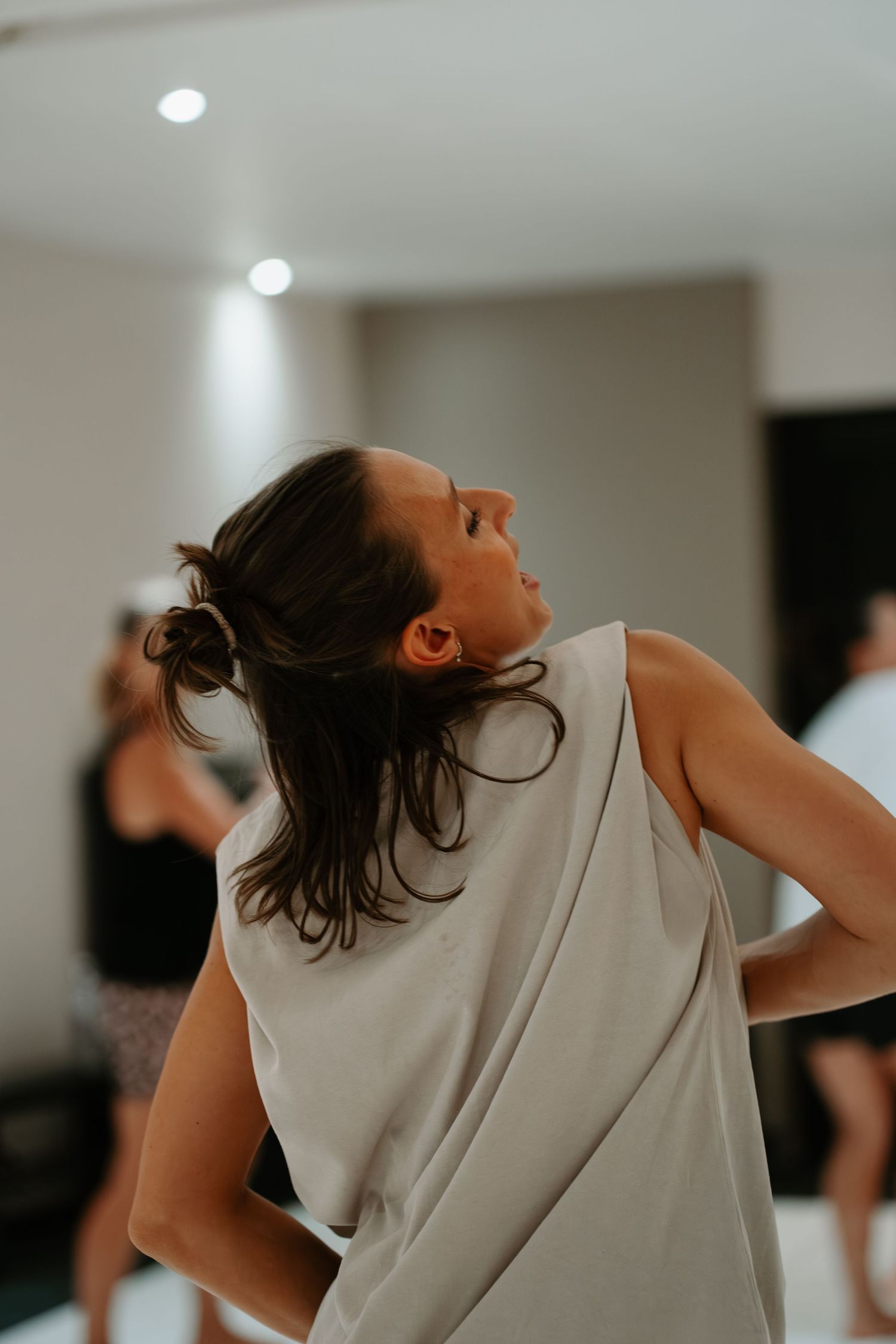 A dancer in a white sleeveless top moves expressively during a contemporary dance performance.