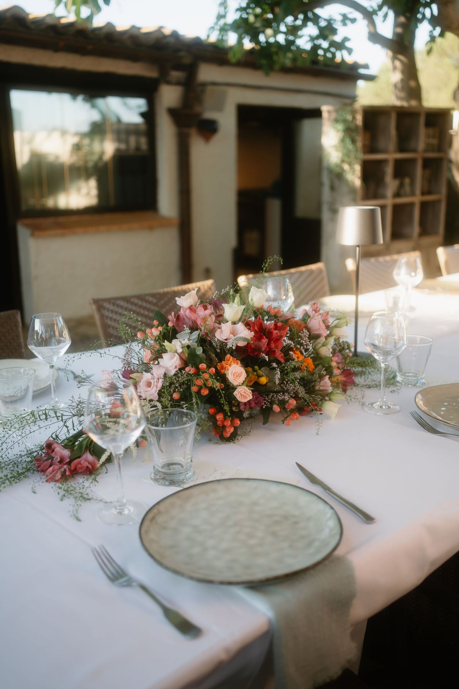 Elegant wedding table settings with floral centerpieces and white linens in an outdoor venue.