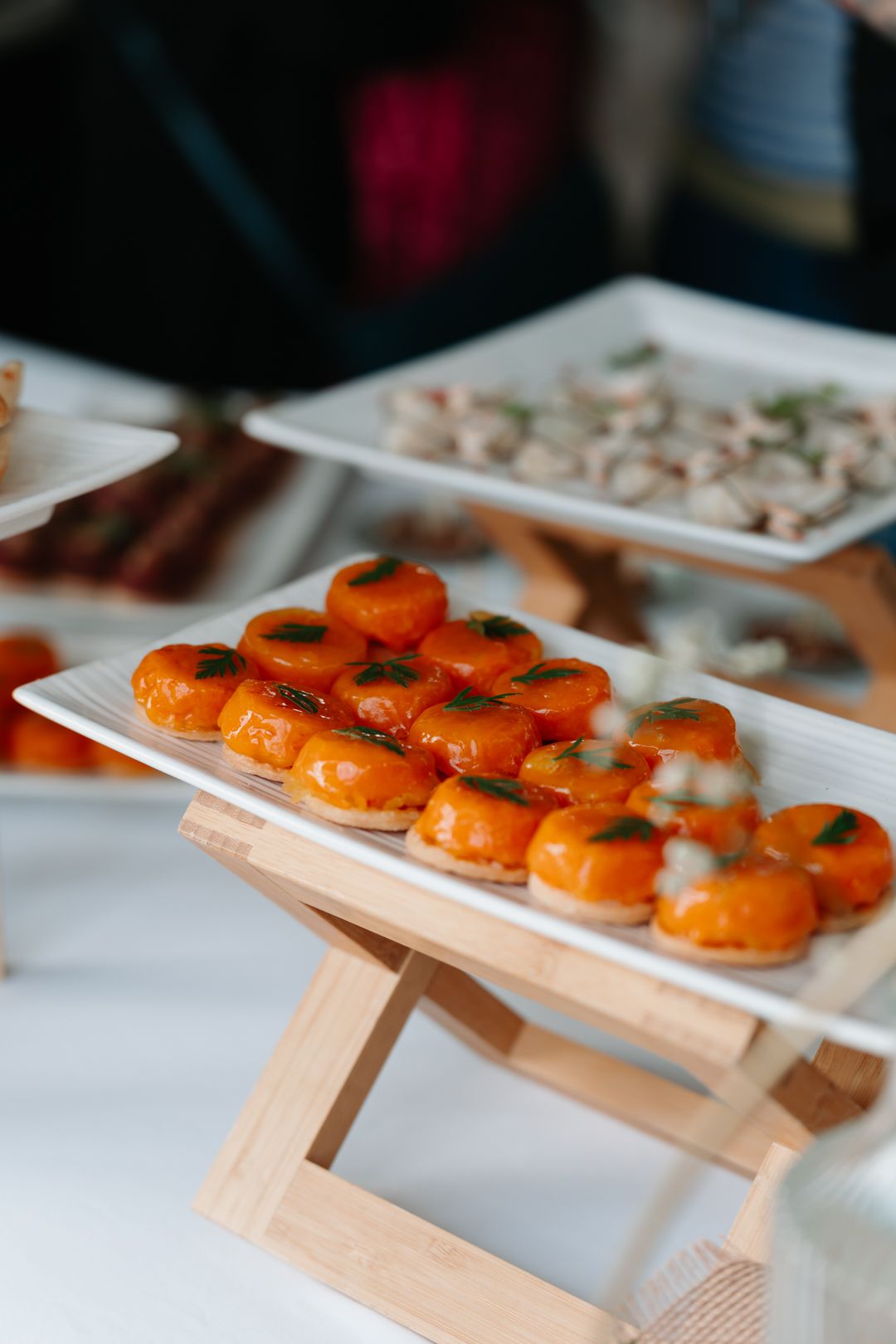 Fresh salmon sushi rolls arranged on white plates and wooden serving boards in a modern restaurant setting.