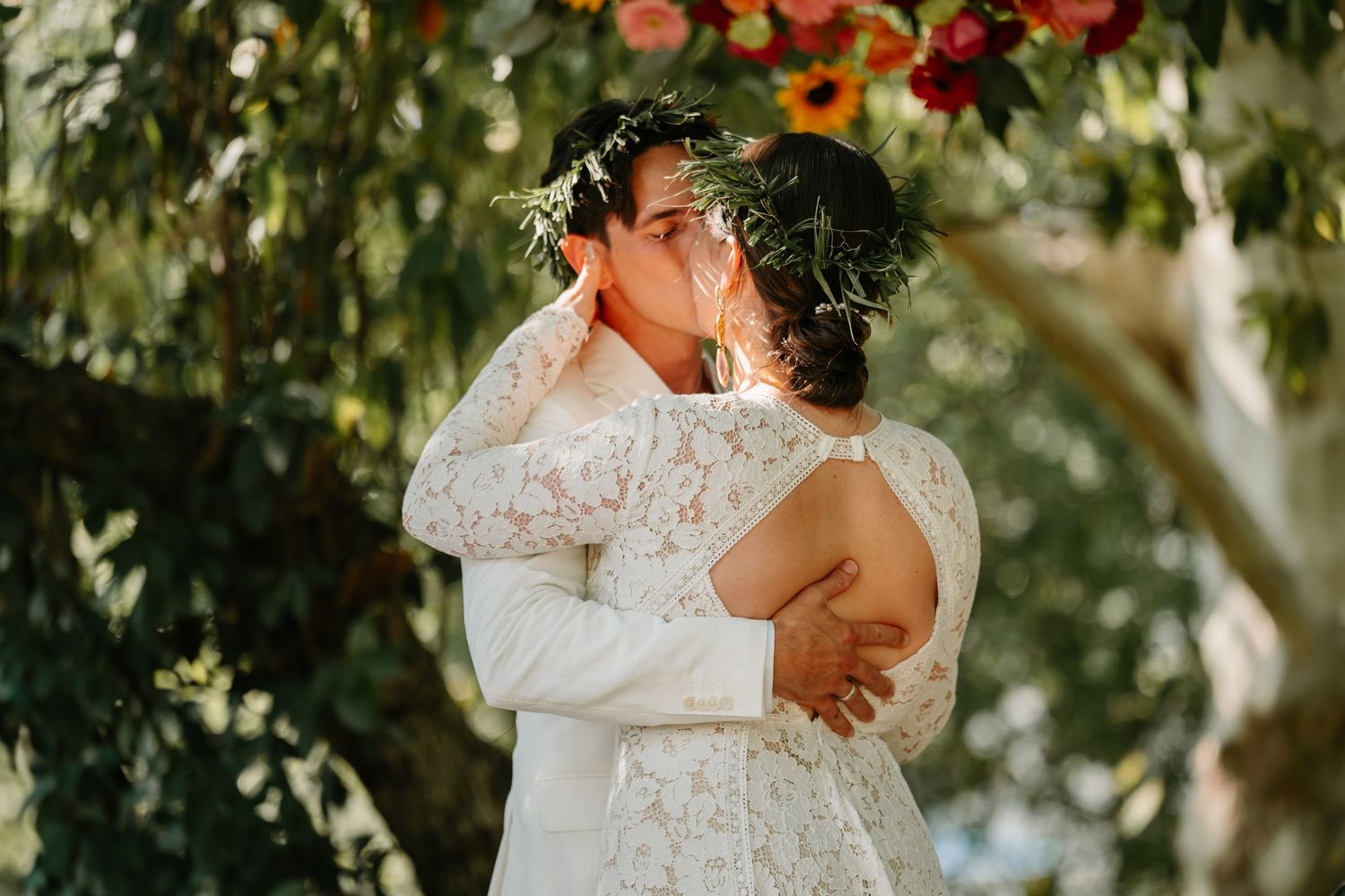 A couple embraces during a romantic outdoor wedding ceremony surrounded by lush greenery and natural light.