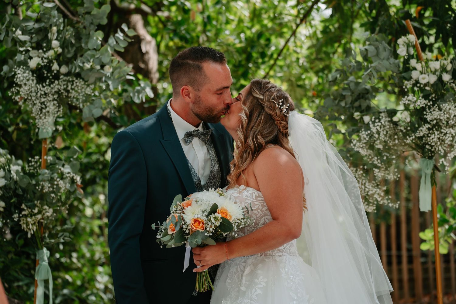 A couple shares an intimate moment in a lush garden setting during their outdoor wedding ceremony.