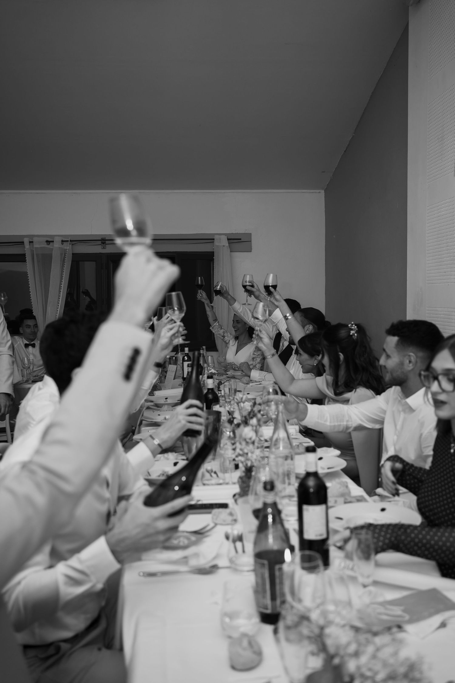 A sequence of black and white photos showing a group of people raising their hands in celebration at a dinner table.