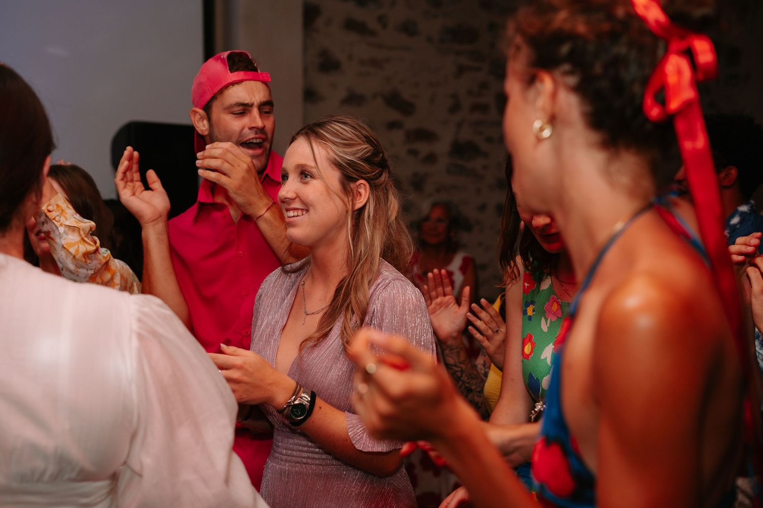 People dancing and celebrating at a lively party with red lighting and a festive atmosphere.