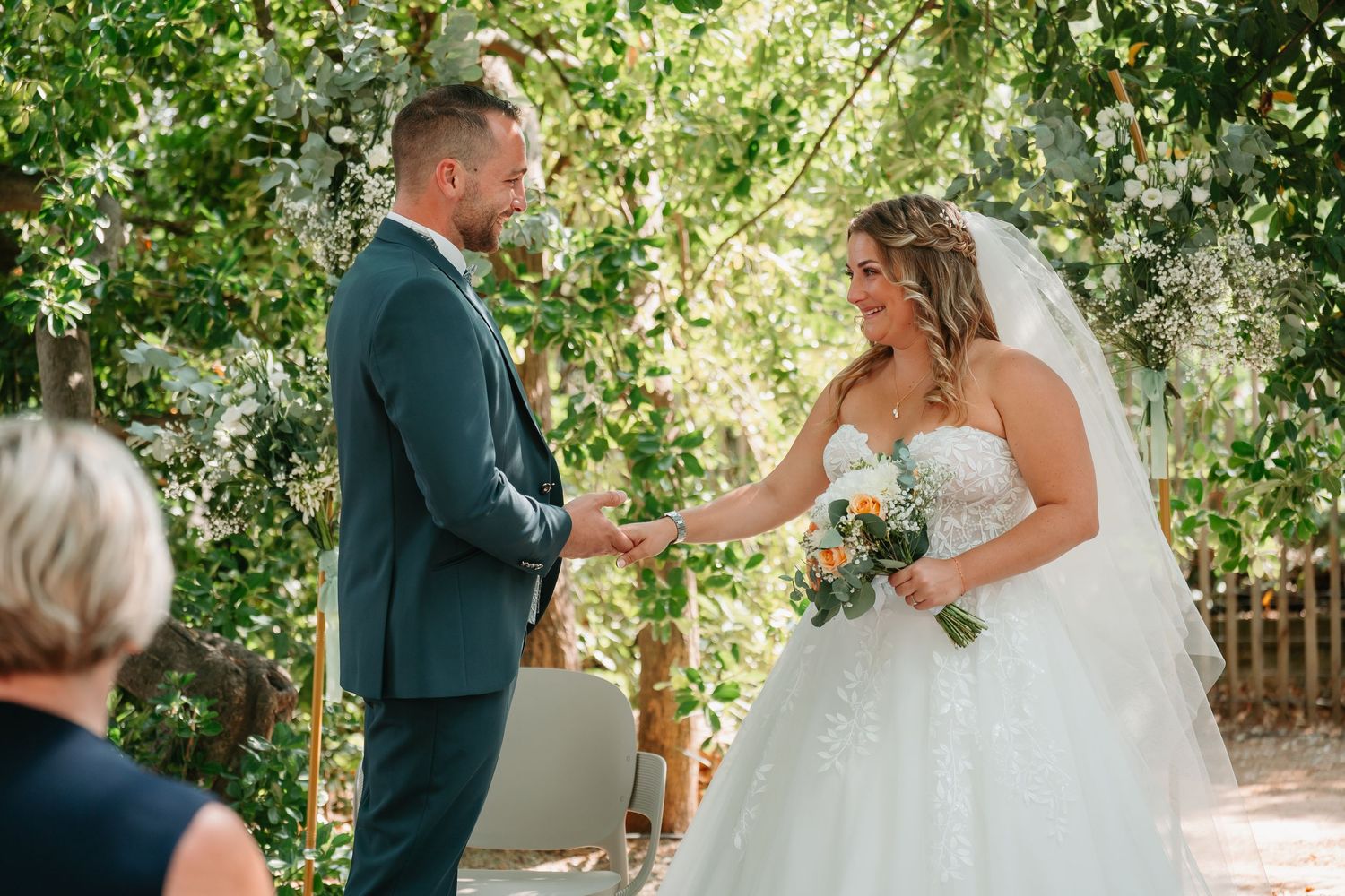 Wedding couple shares intimate moments during outdoor garden ceremony with natural greenery backdrop.