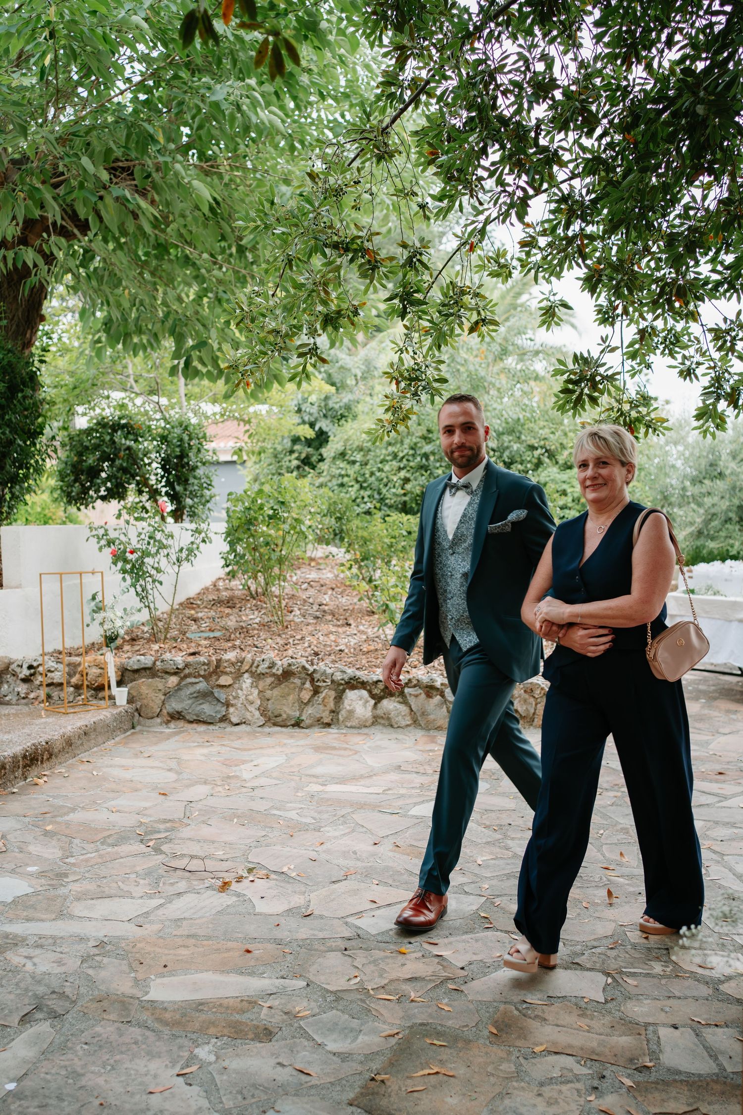 A series of playful dance poses captured on a stone patio beneath green trees in an outdoor garden setting.