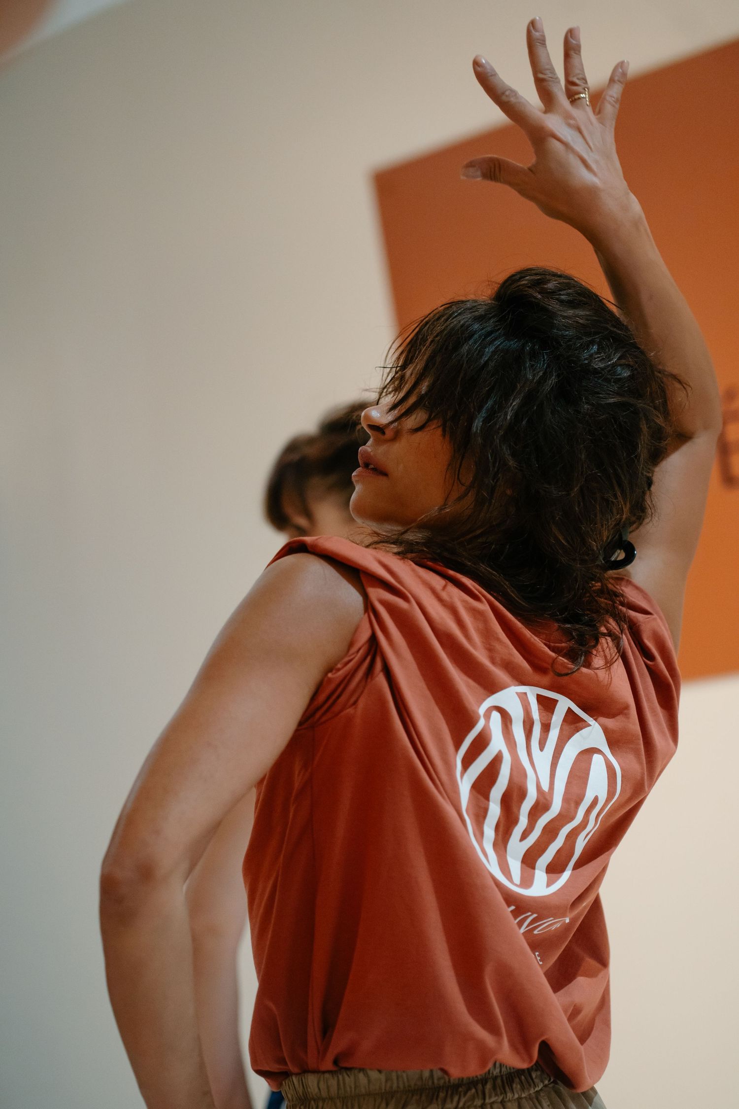 Person in coral t-shirt dancing against white wall with dynamic arm movements in sequence of connected photos.