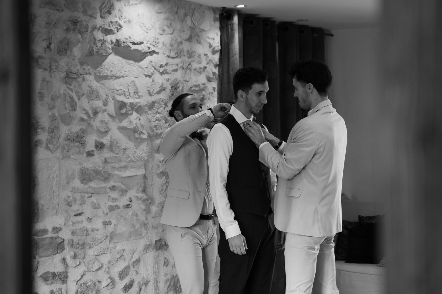 A black and white wedding photo shows a couple embracing while dancing in a rustic stone-walled venue.