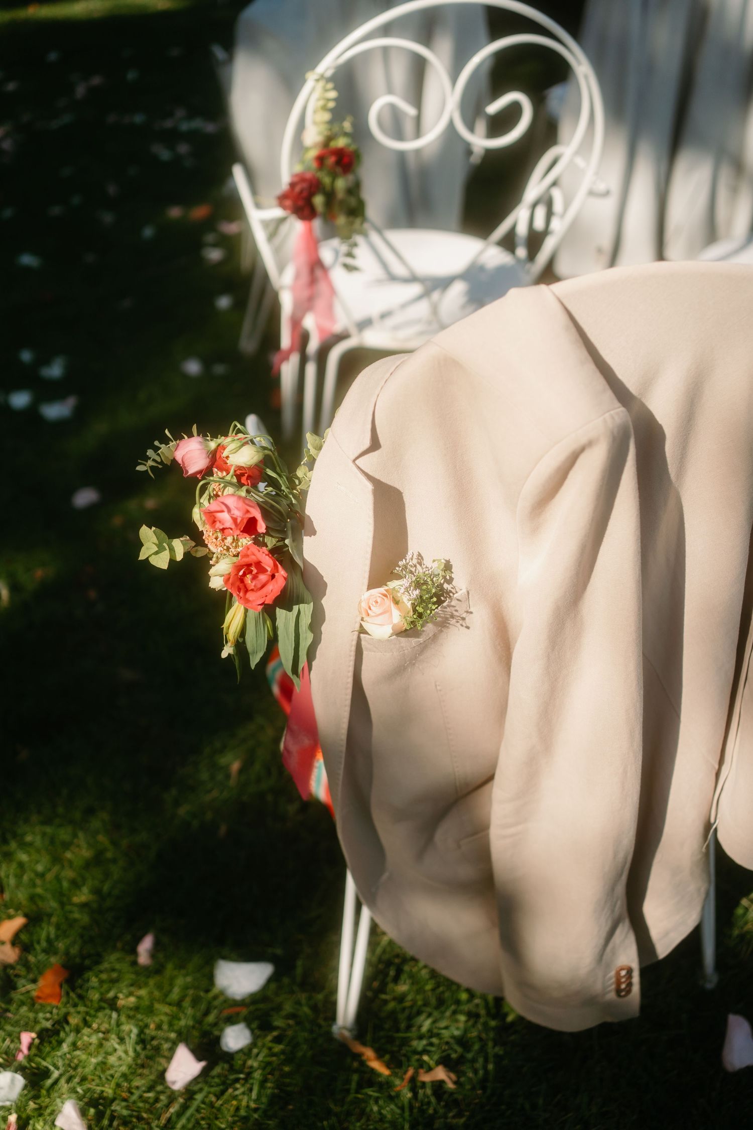 Elegant white fabric draped on hangers adorned with delicate coral roses and greenery in a garden setting.
