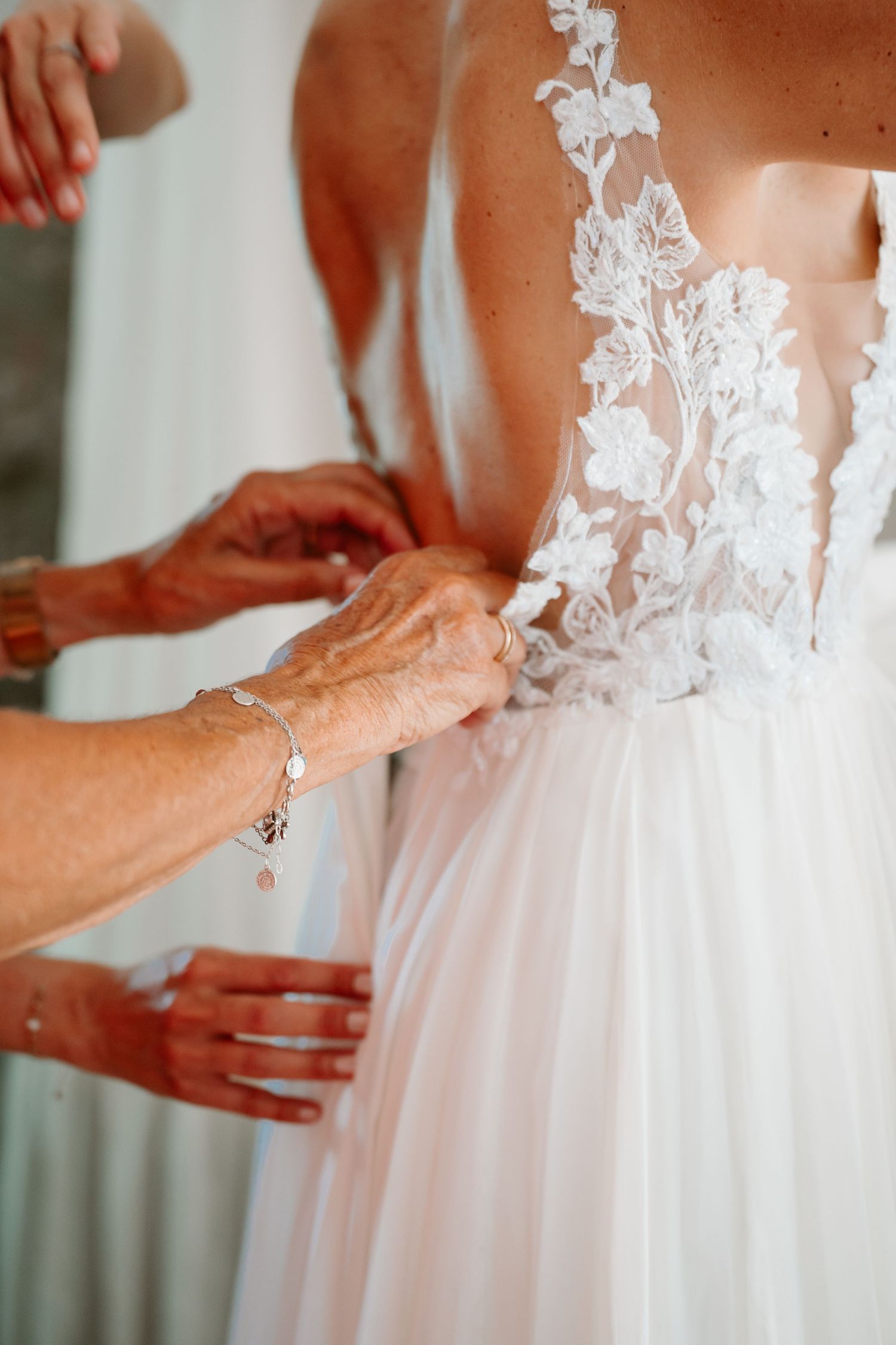 Hands adjusting the delicate lace details on a white wedding dress bodice in a series of close-up shots.