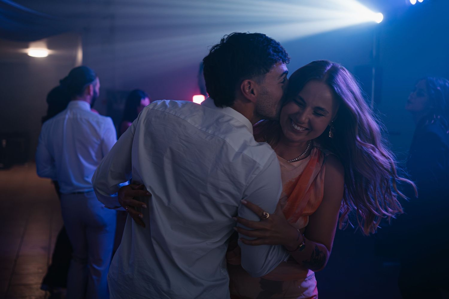 Couples dancing together in a dimly lit nightclub with blue and purple lighting effects.