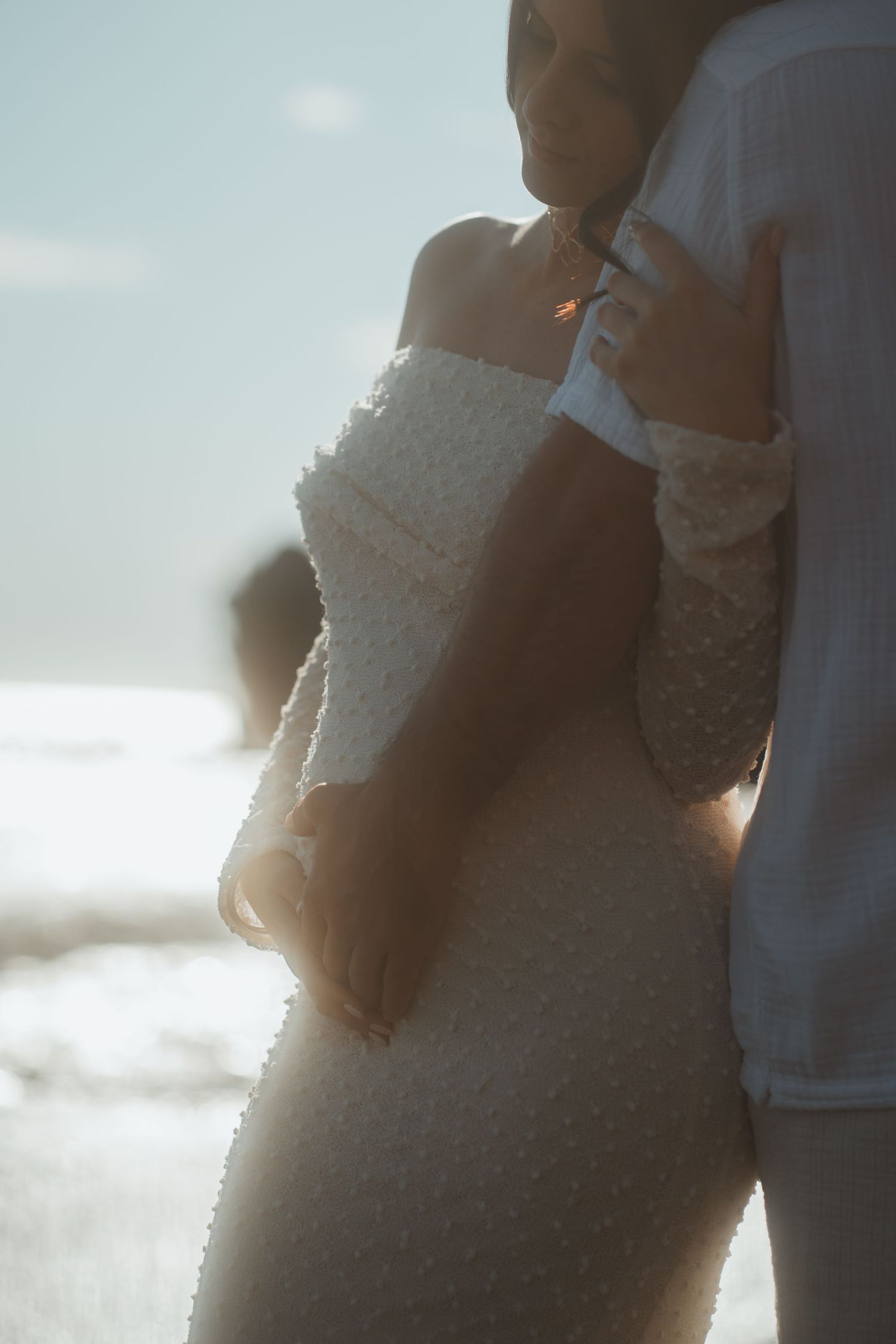 Intimate silhouette of couple in wedding attire against ocean backdrop.