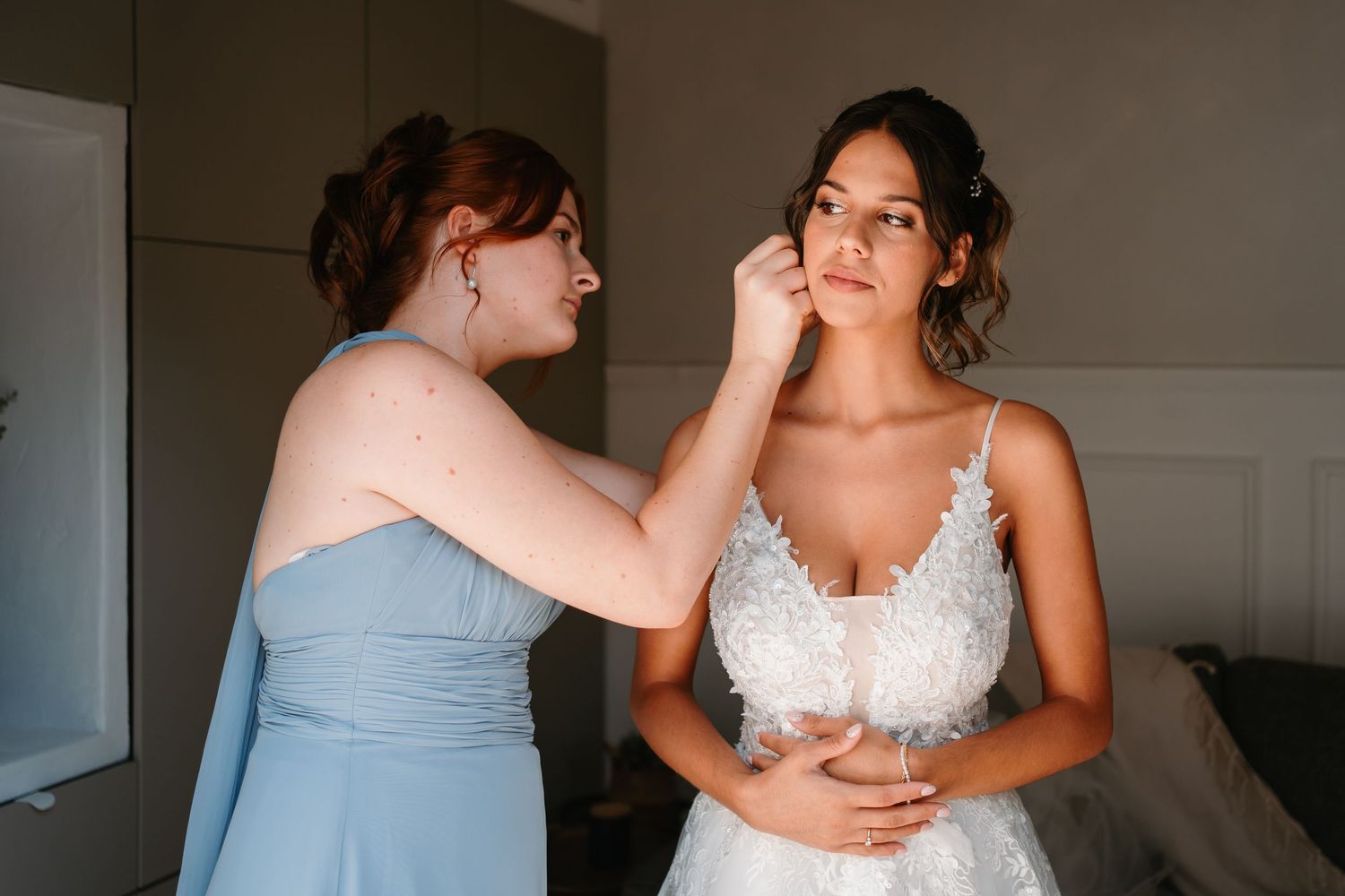 Intimate getting ready moment as bridesmaids help with wedding dress preparations.