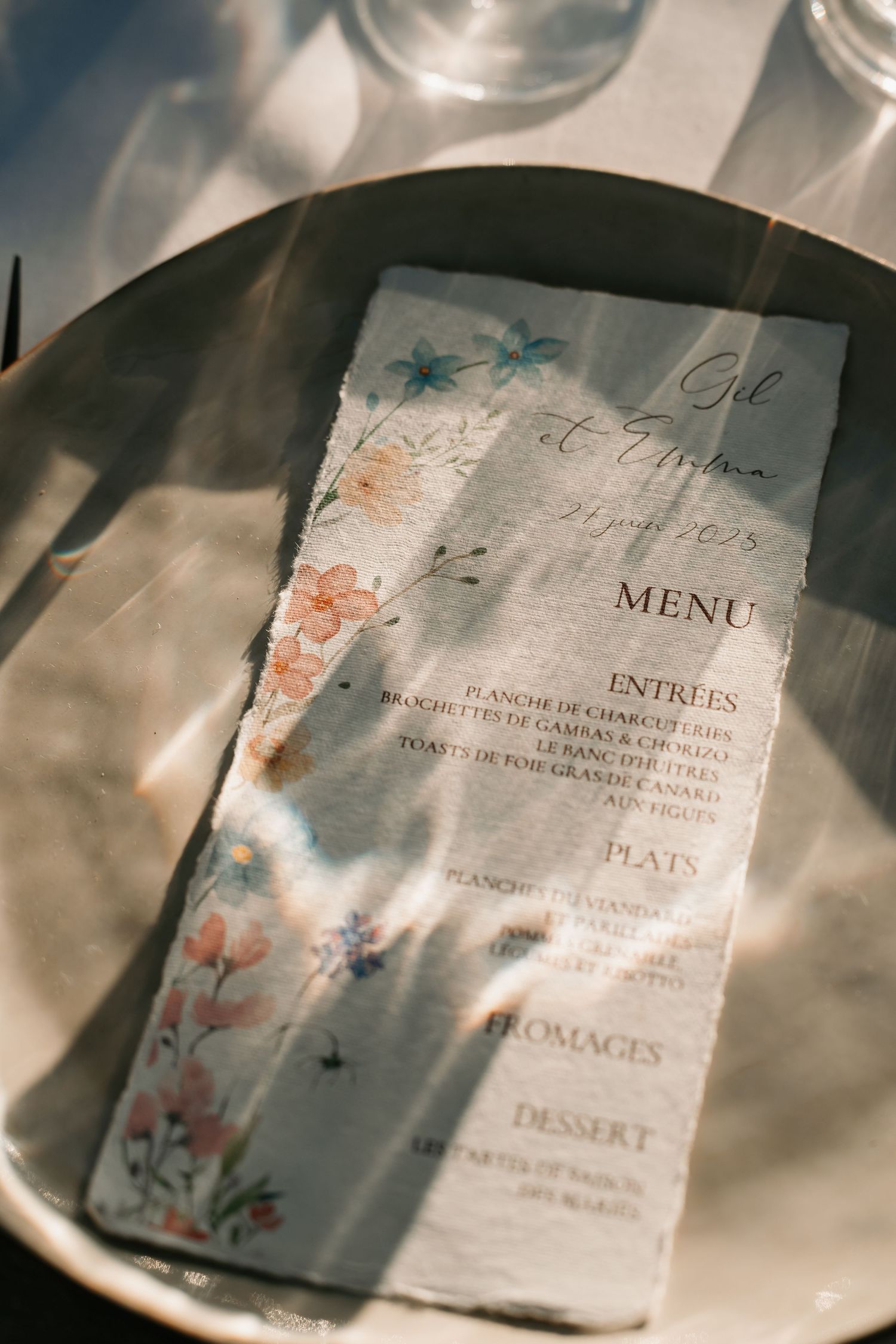 Elegant wedding menu cards with delicate floral watercolor designs and calligraphy text displayed on white plates.