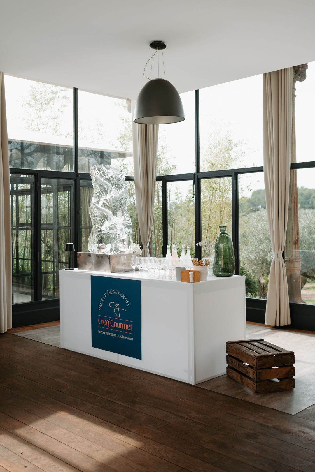 Modern office interior with dark hardwood floors, white walls, and large windows overlooking natural scenery.