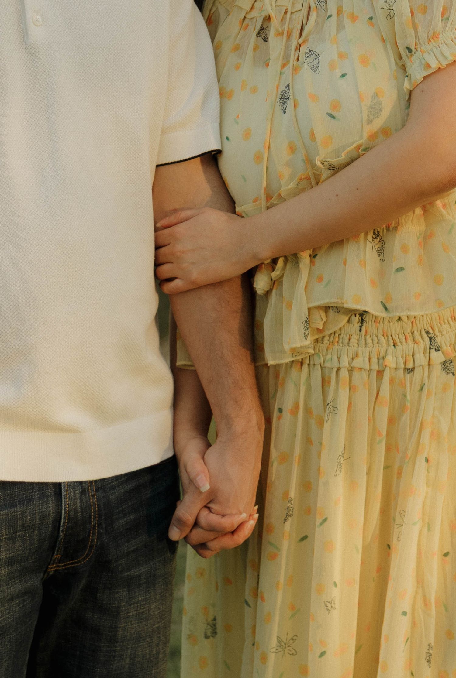 A series of cropped photos showing two people holding hands against a background of cream colored floral fabric.