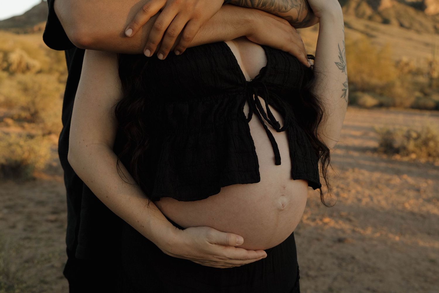 A series of intimate maternity photos showing a pregnant woman's belly in a black dress against a desert landscape at sunset.