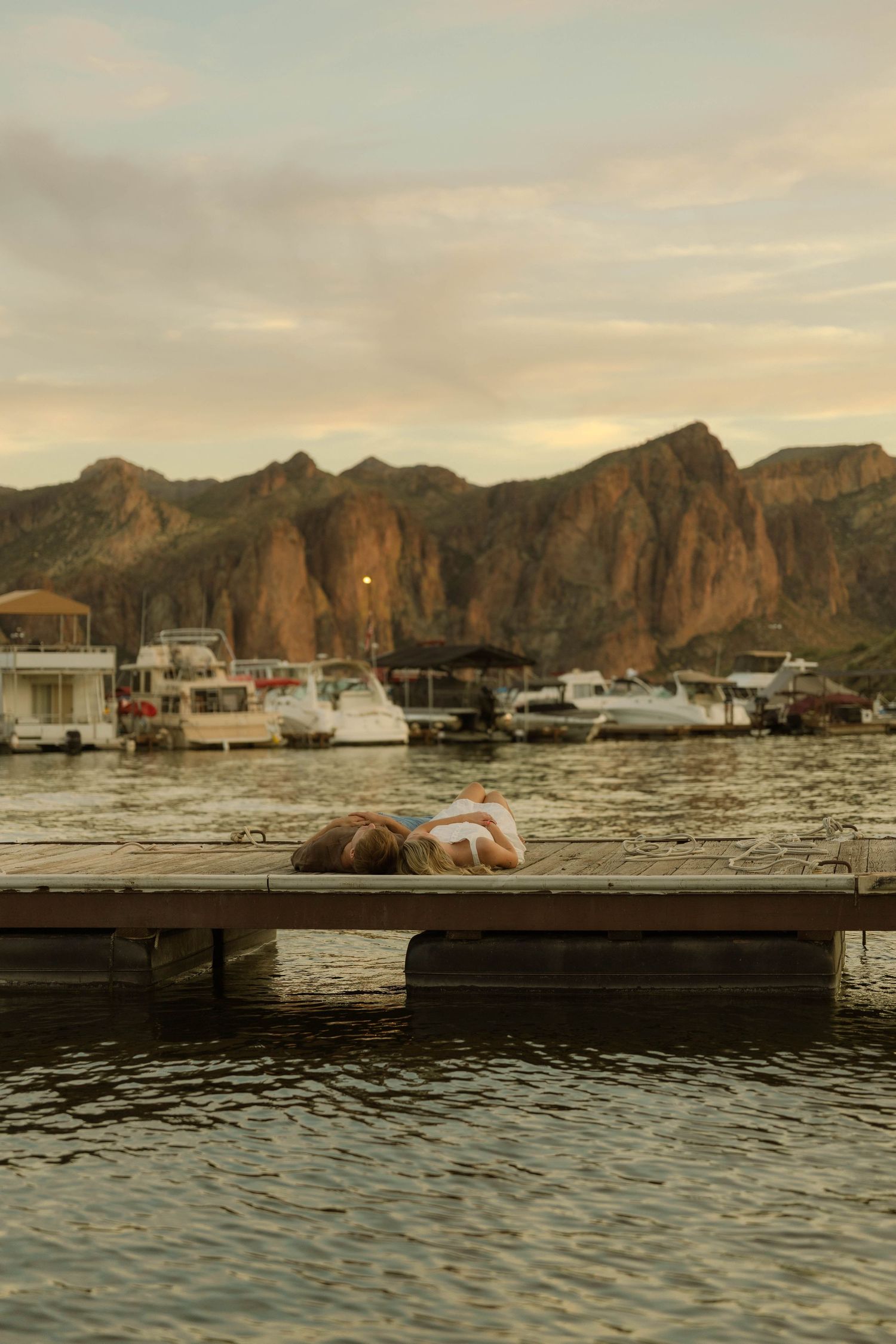A scenic lakeside moment on a dock with mountains and boats in the distance.