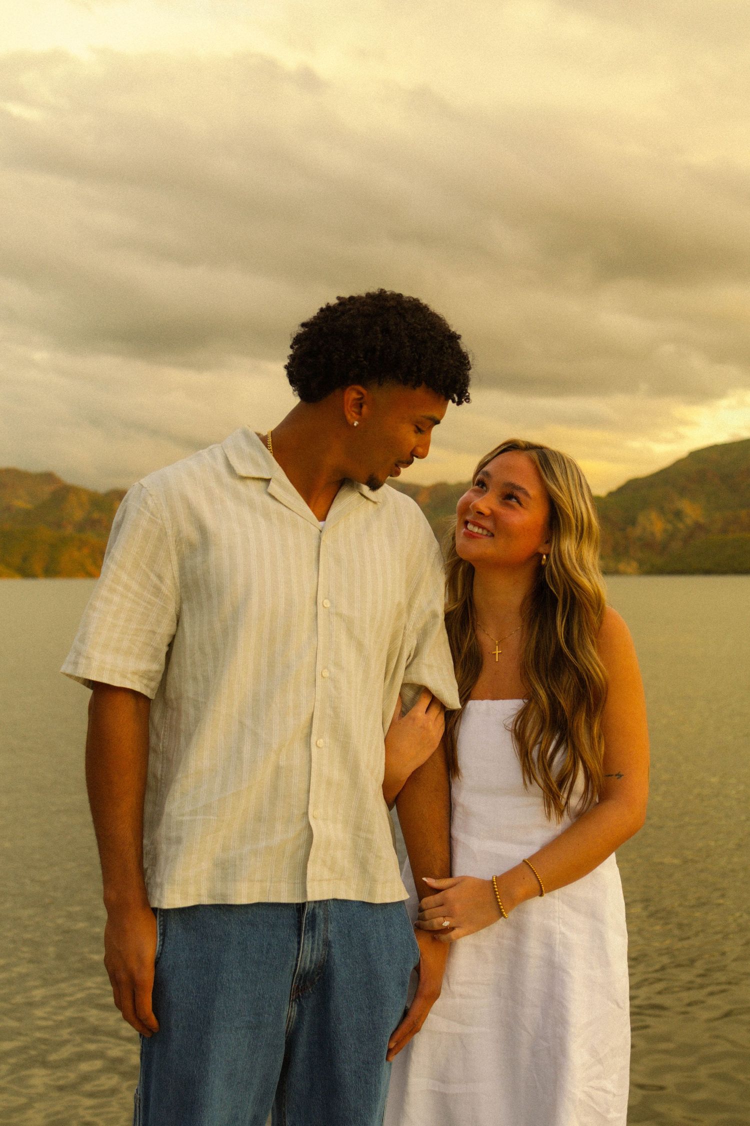 A couple shares intimate moments by a lake at sunset in a series of romantic candid photos.