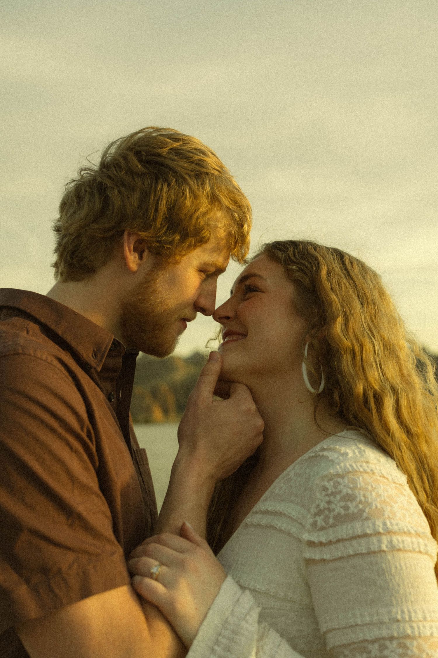 A romantic couple shares an intimate moment at sunset with golden light illuminating their faces.