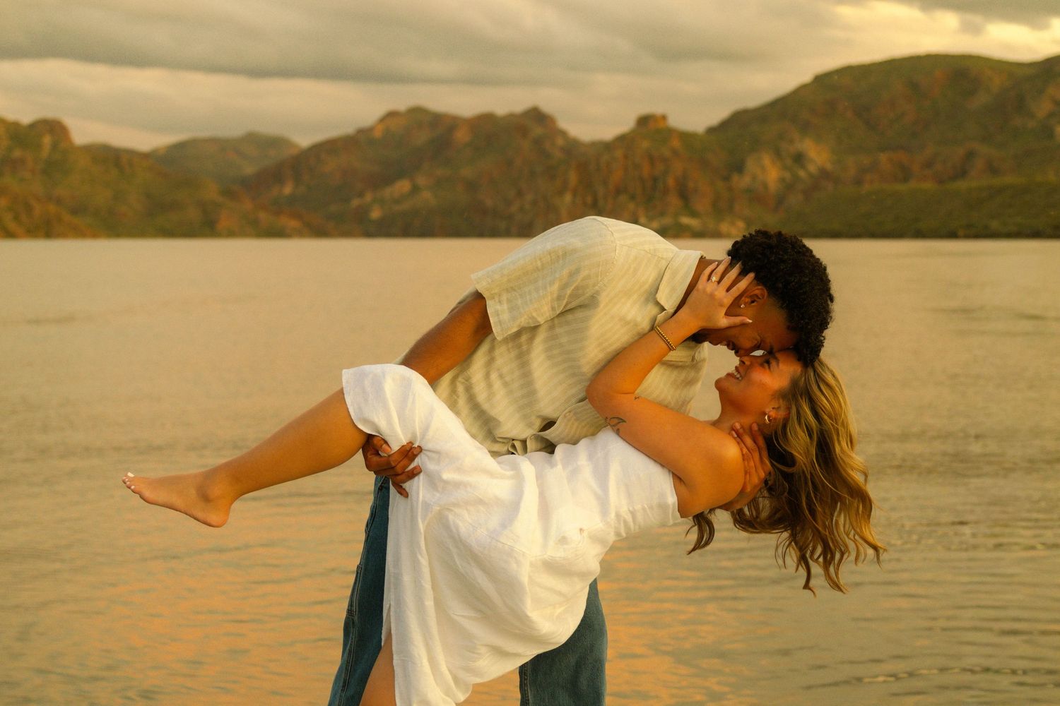 A sequence of dance movements performed at sunset by a lake with mountains in the background.