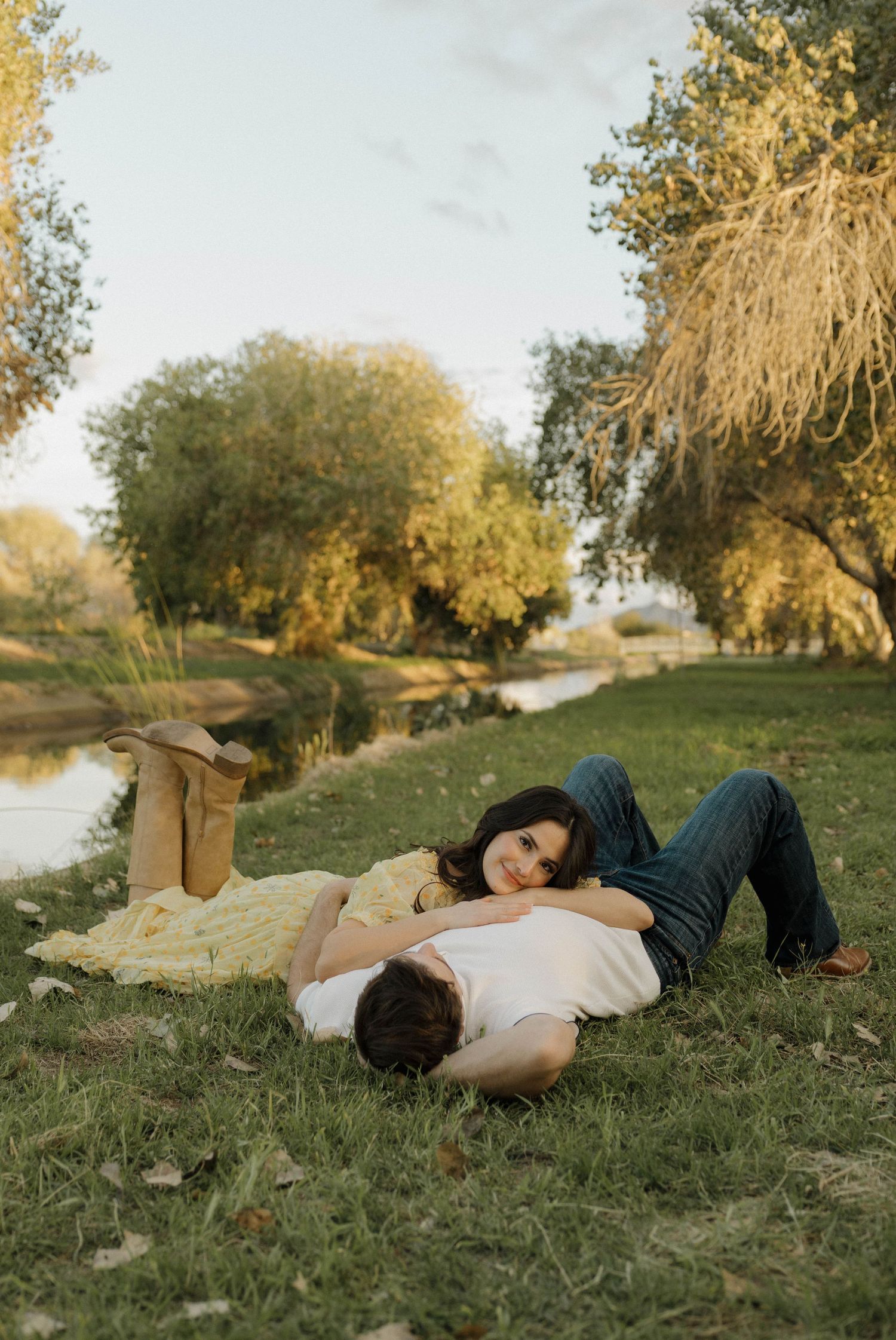 Couple lying on grass together enjoying peaceful moment in nature during sunset.