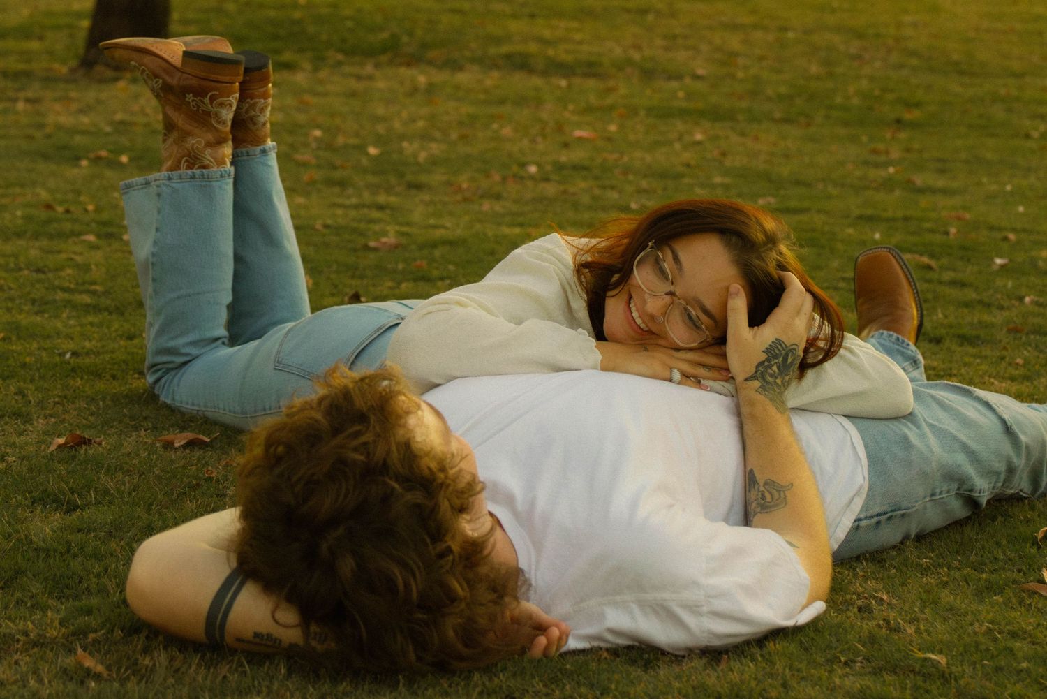 Person lying on grass in casual clothing rolls over in a series of sequential movements.