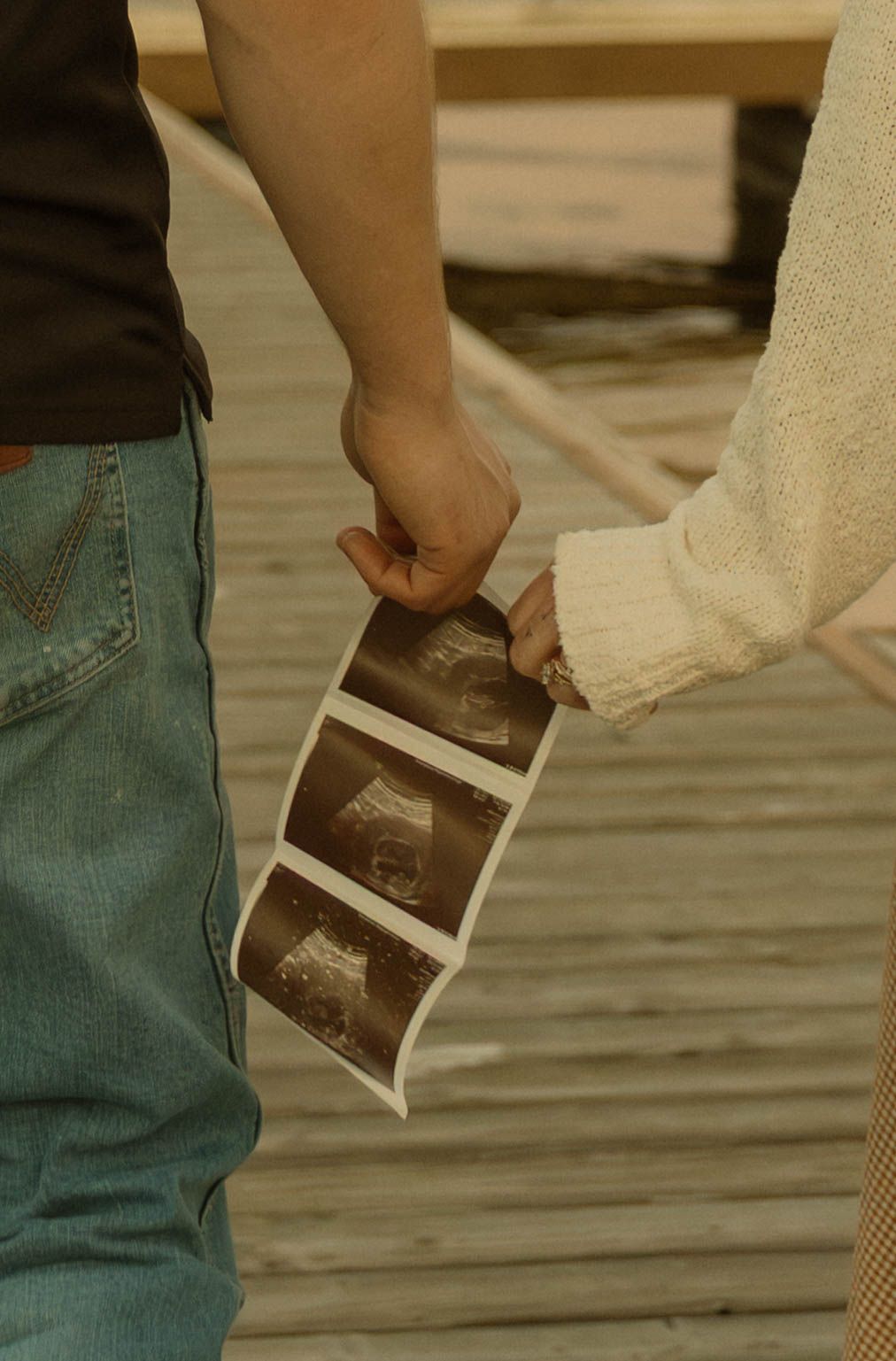 A sequence of images showing hands tearing a photograph into pieces while wearing blue jeans.