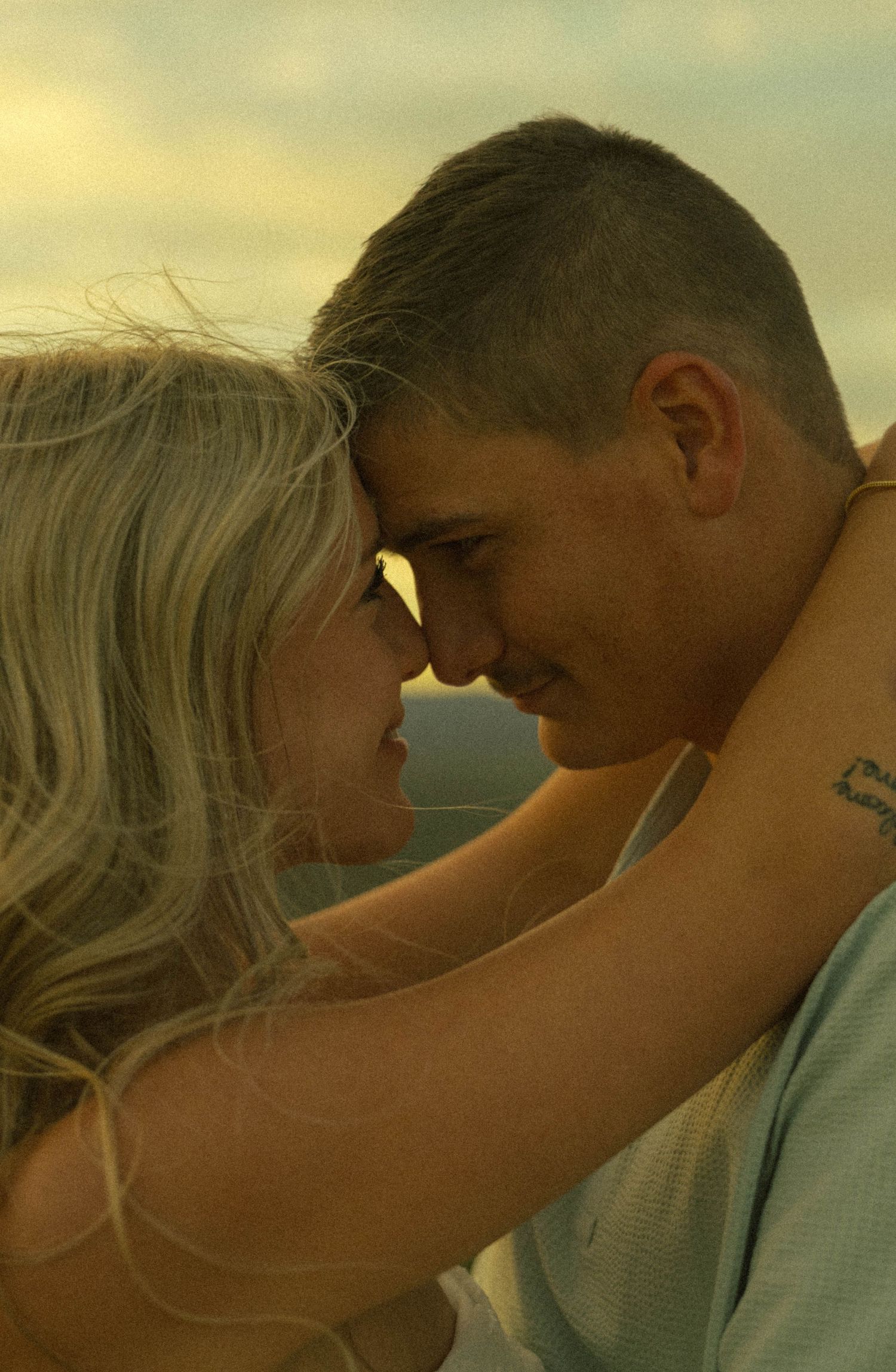 Romantic couple embracing forehead to forehead during a glowing outdoor golden hour photo session.