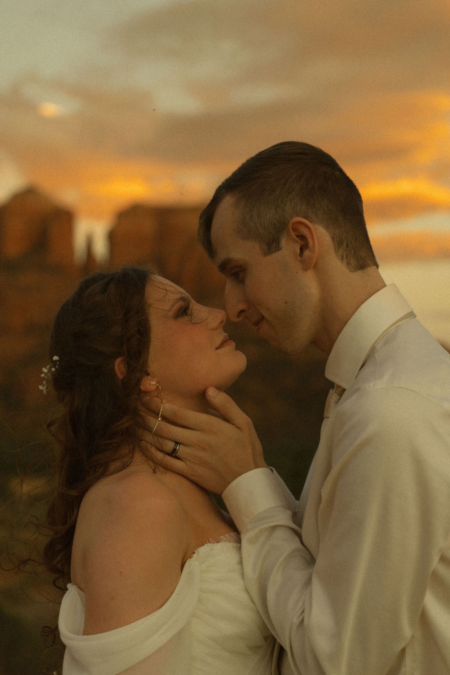 Bride and groom share a romantic almost-kiss at sunset, with golden skies and red rock formations in Sedona, AZ.
