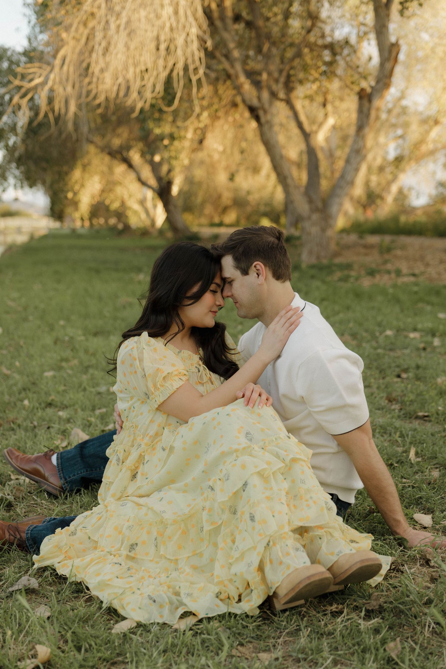 Couple lying on grass in a romantic pose with flowing yellow dress.