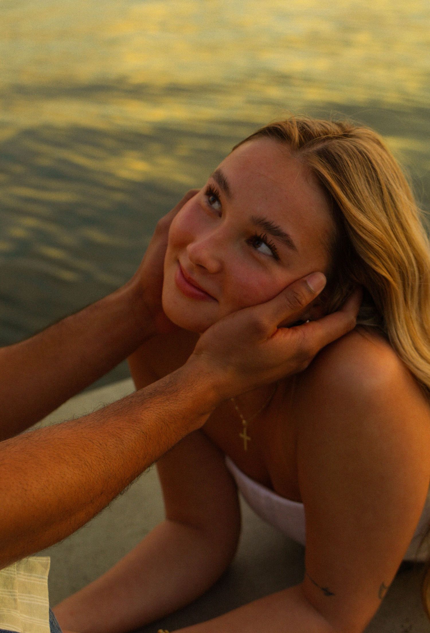 Woman lying down on a wooden deck during sunset with warm golden lighting.