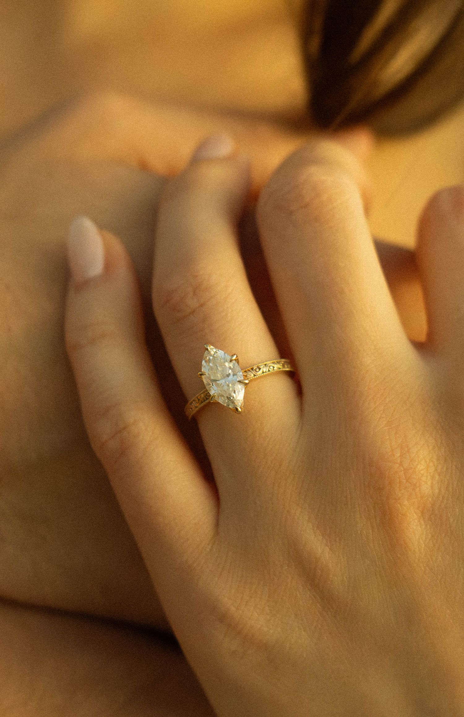 A delicate engagement ring with a light blue stone sparkles in warm golden lighting.