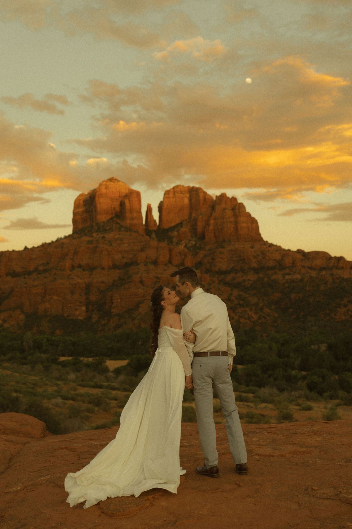 Couple sharing a romantic kiss at sunset with Cathedral Rock in Sedona, Arizona glowing golden behind them.