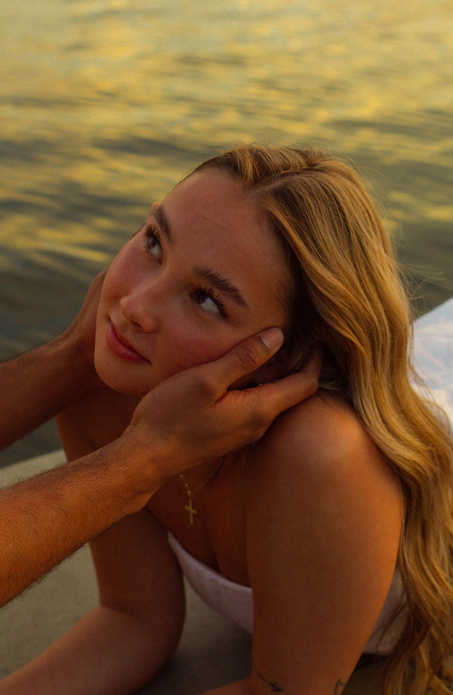 A close-up portrait of someone reclining by a lake during golden hour.
