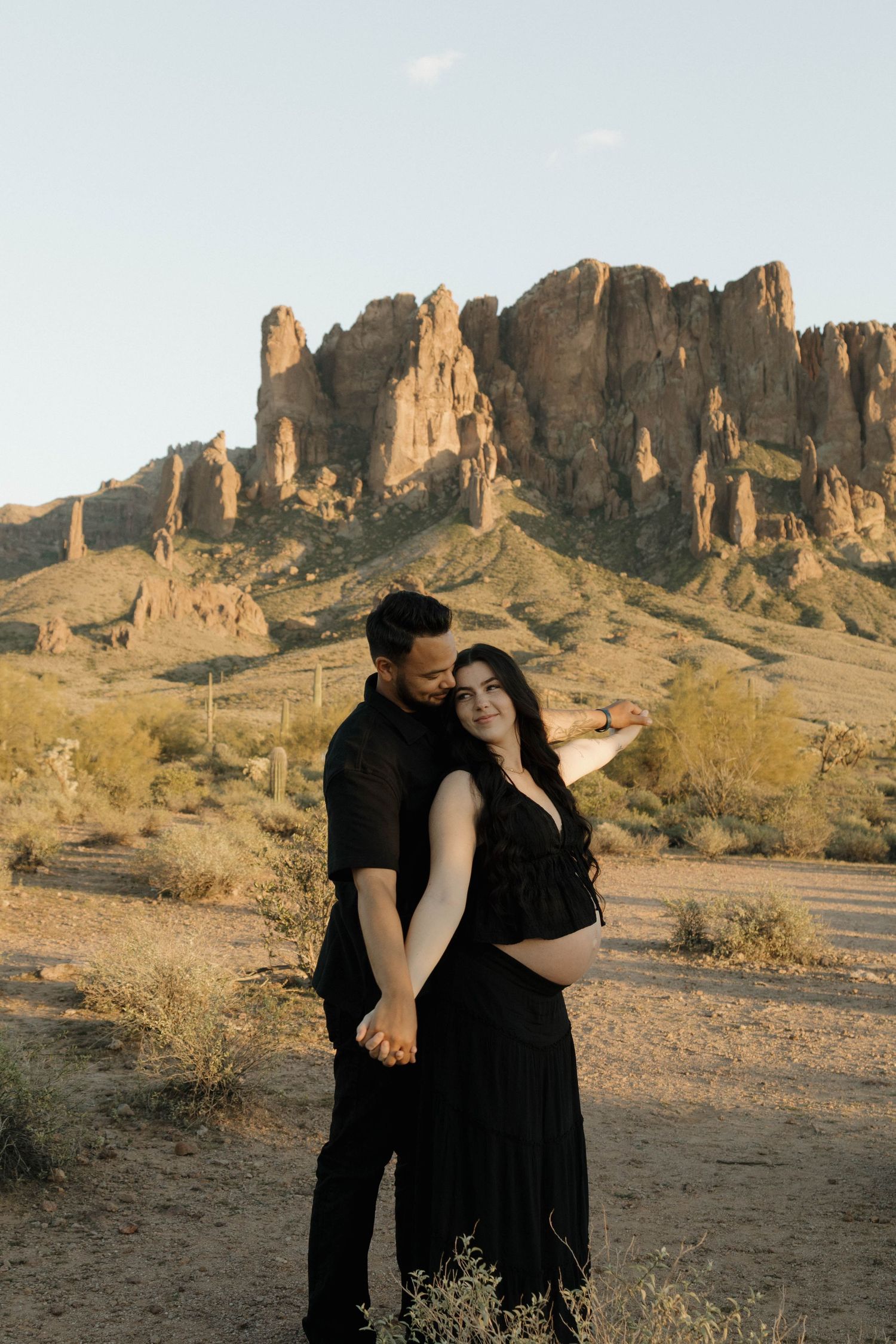 A couple shares intimate moments against the backdrop of majestic desert cliffs during golden hour.