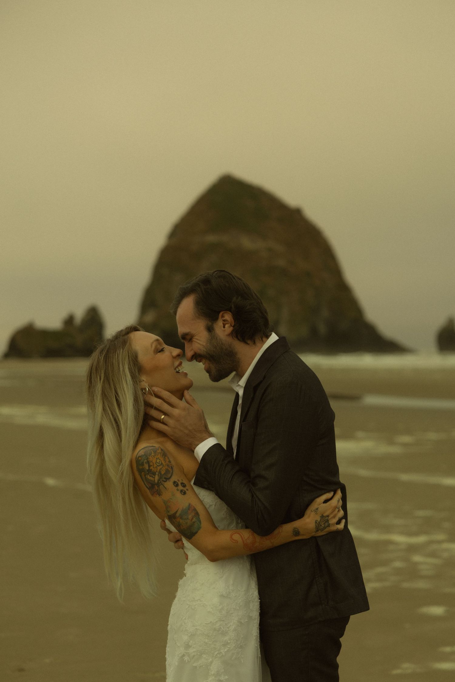 Couple sharing a romantic moment on Cannon Beach with iconic Haystack Rock backdrop on their wedding day.