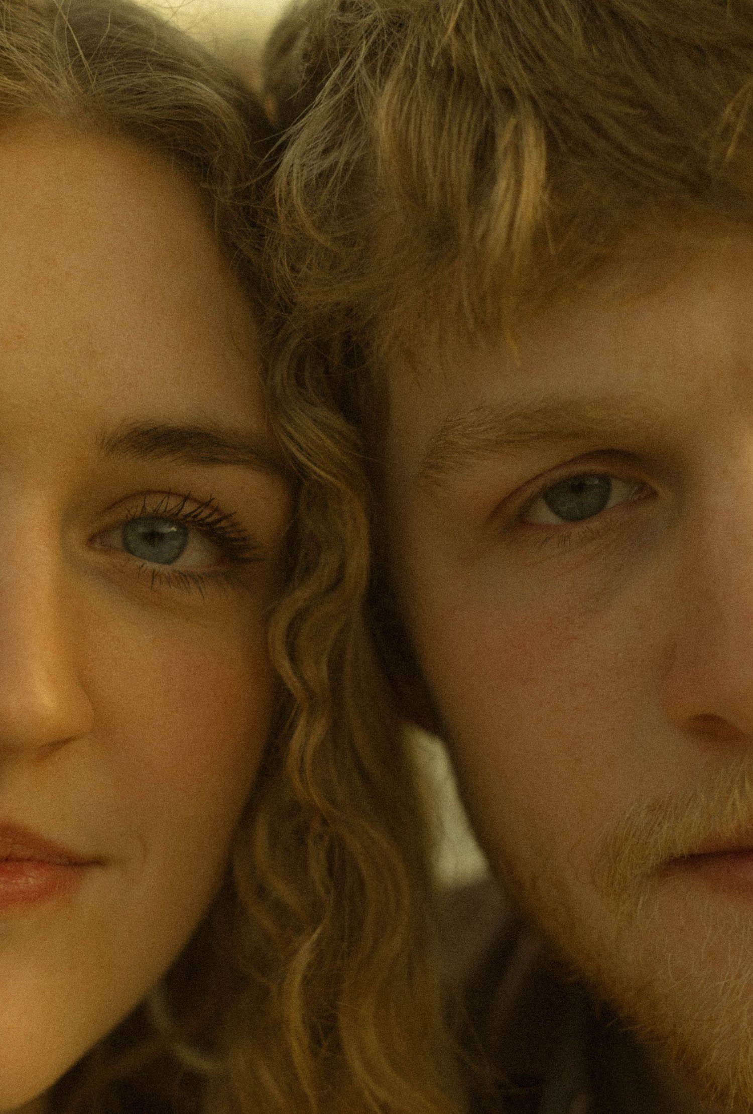 Close up portrait of a couple with curly hair in warm lighting showing half their faces.