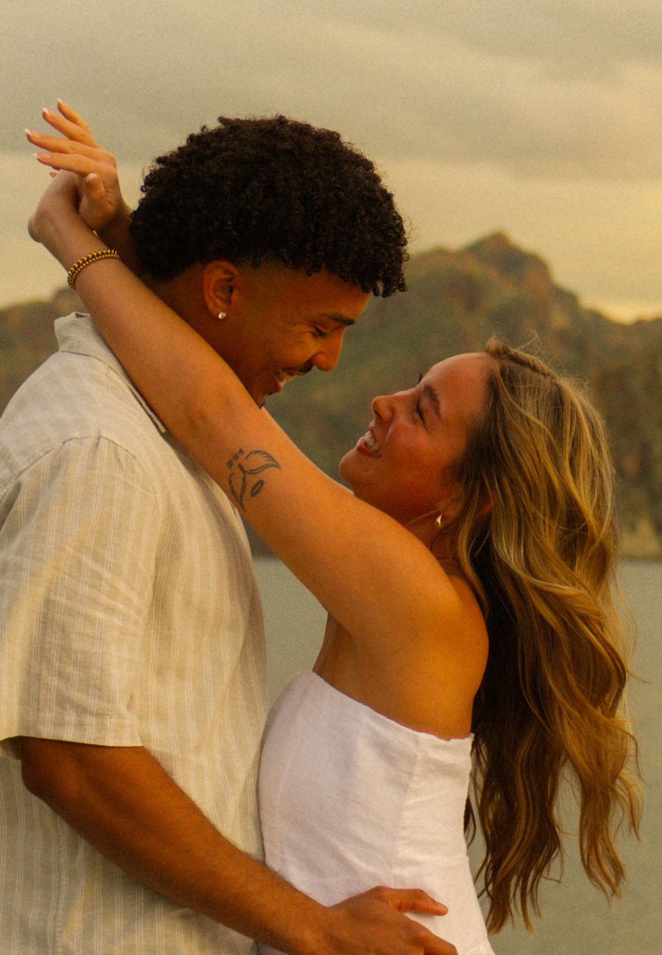 A romantic couple embraces during sunset at the beach, creating a series of intimate candid moments in golden light.