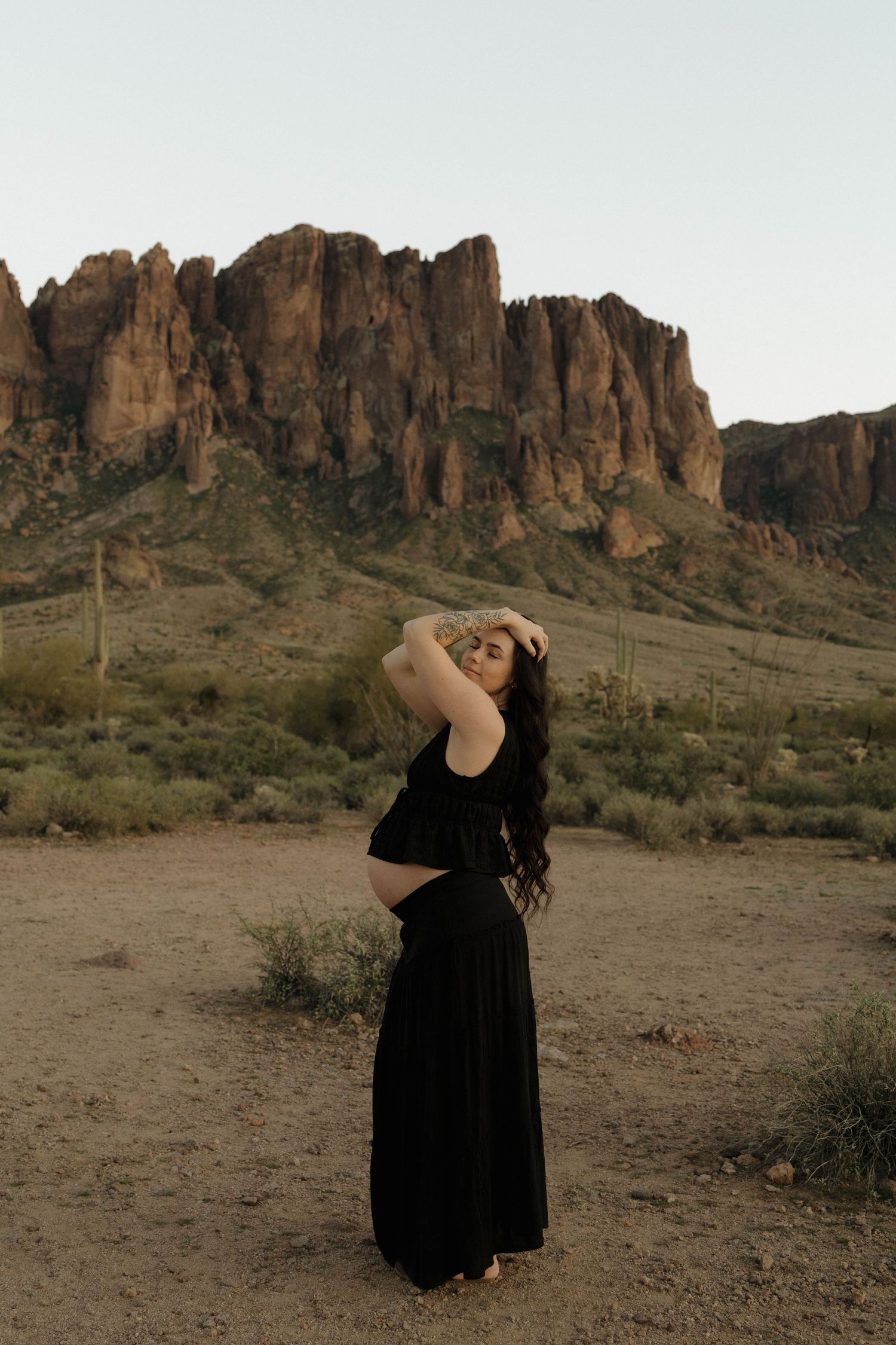 A collection of desert landscape photos showing a figure in a flowing black dress posing against rugged mountain formations.