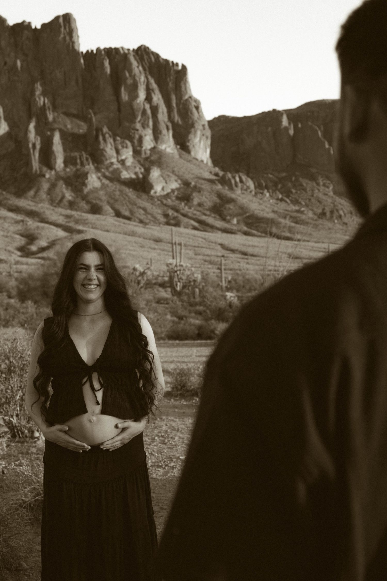 A series of black and white photographs featuring a figure in dark clothing against a dramatic desert mountain backdrop.