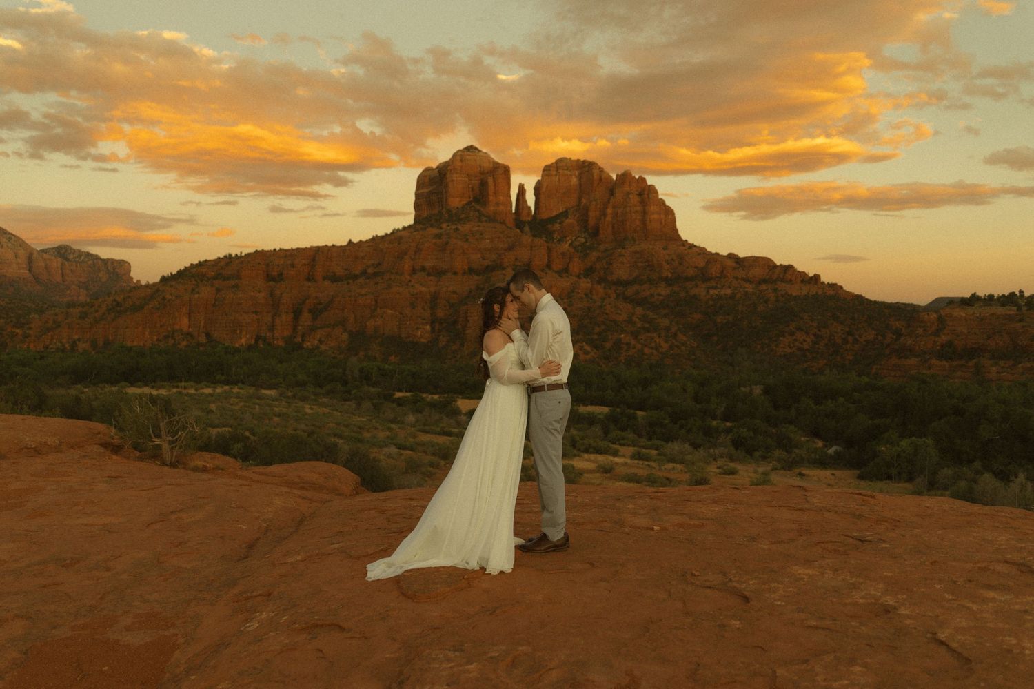 Couple sharing a romantic kiss at sunset with Cathedral Rock in Sedona, Arizona as a stunning backdrop.